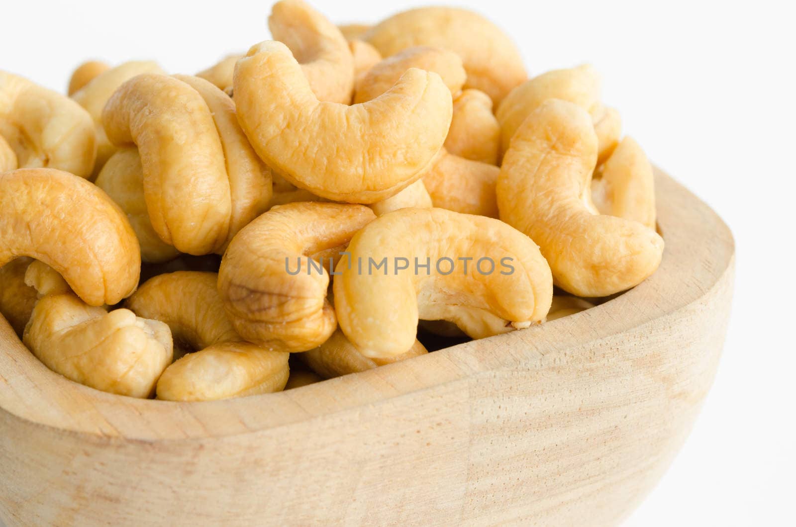 cashew in wooden cup on white background.