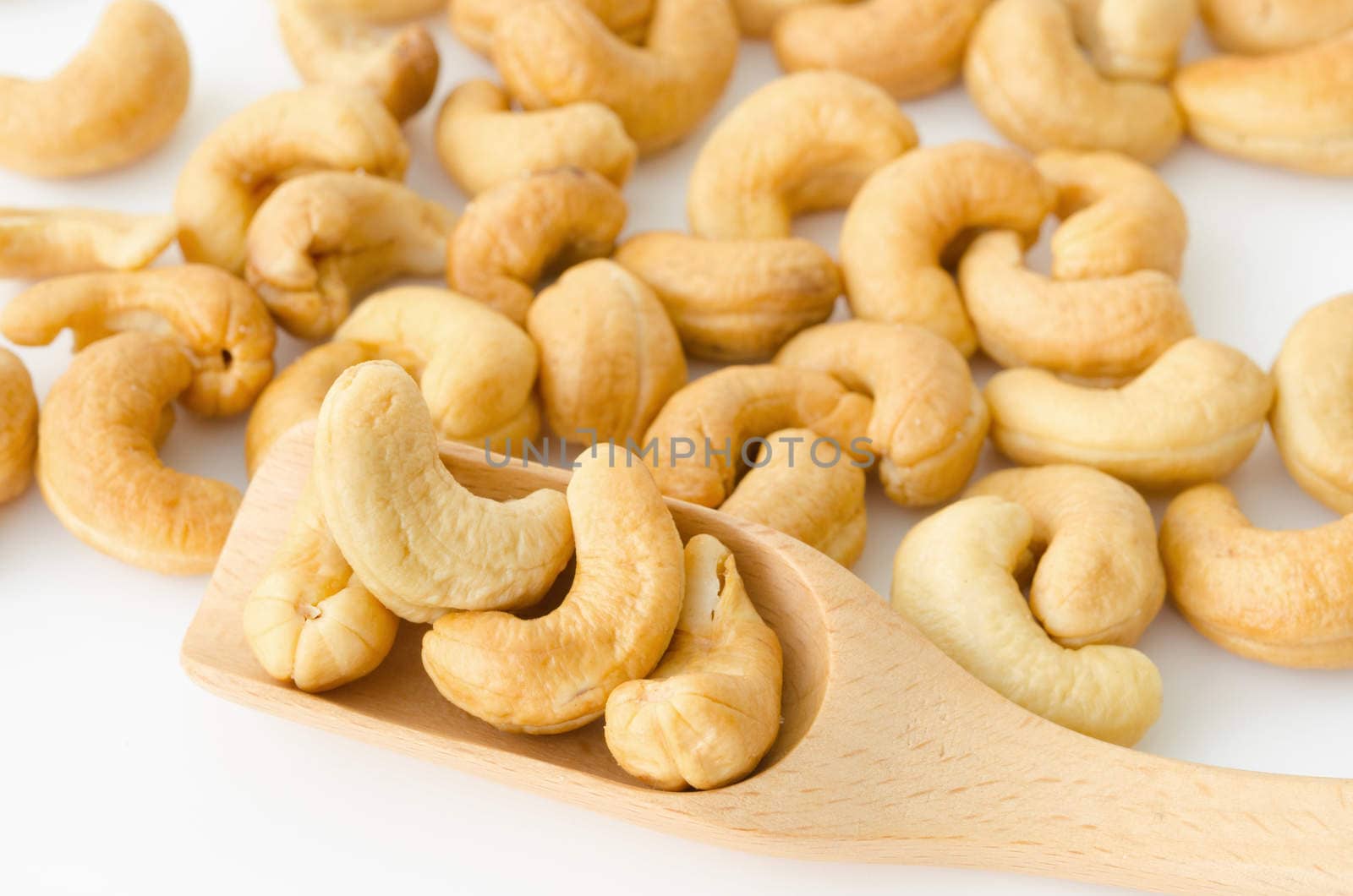 Roasted cashew nuts in wooden spoon. by Gamjai