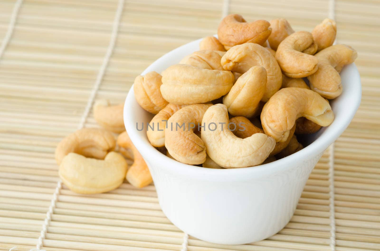 Cashew nuts with salt in white bowl. by Gamjai