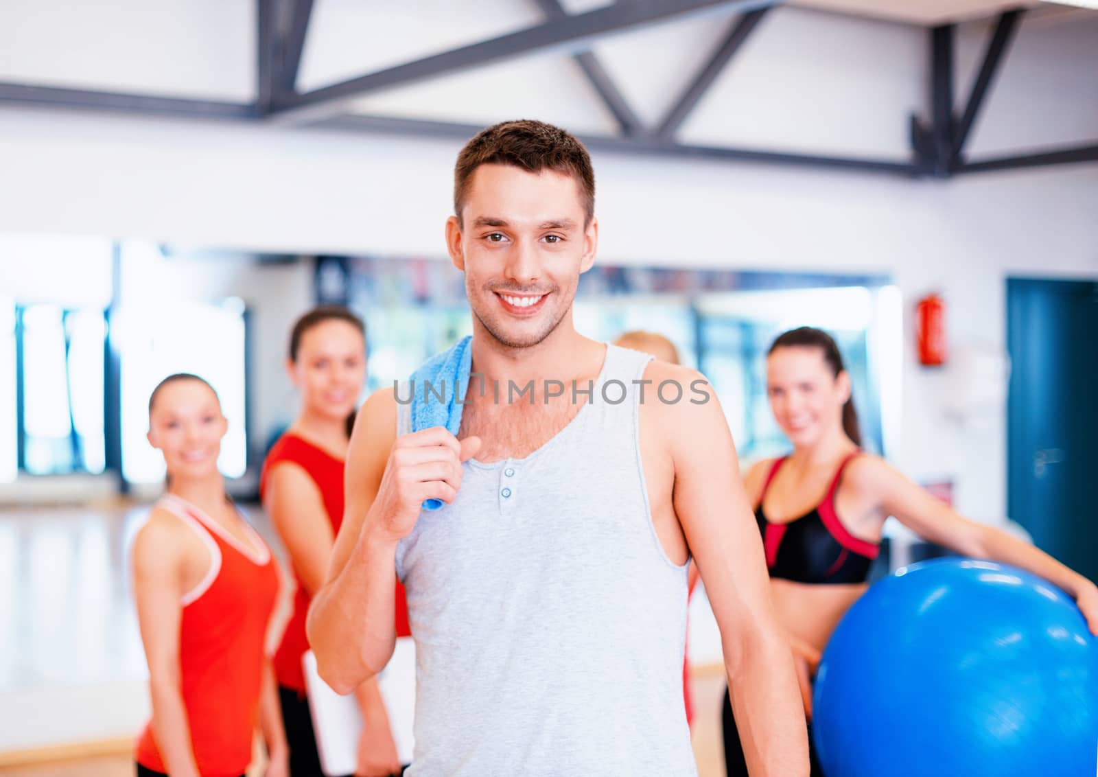 fitness, sport, training, gym and lifestyle concept - smiling man standing in front of the group of people in gym