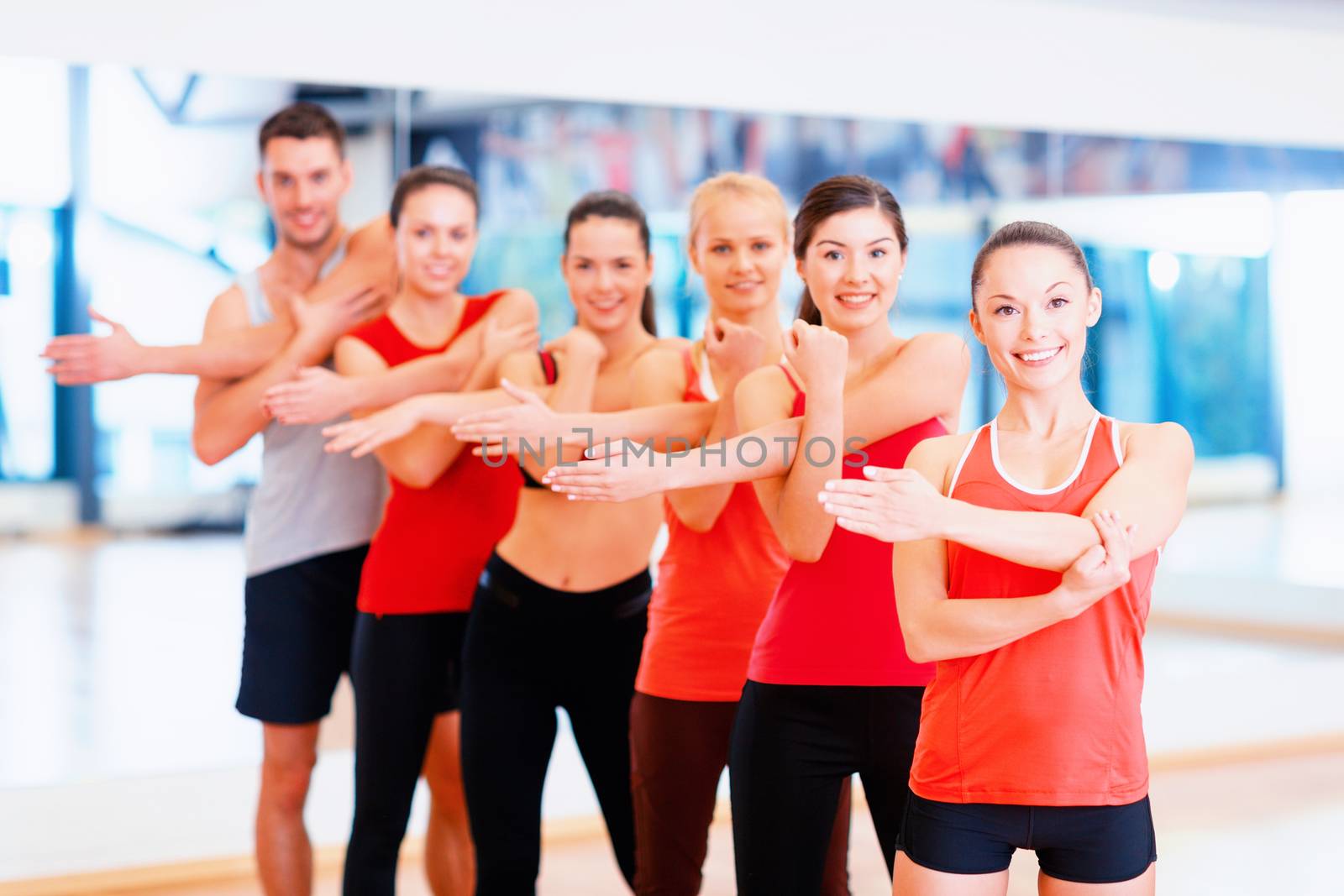 group of smiling people stretching in the gym by dolgachov