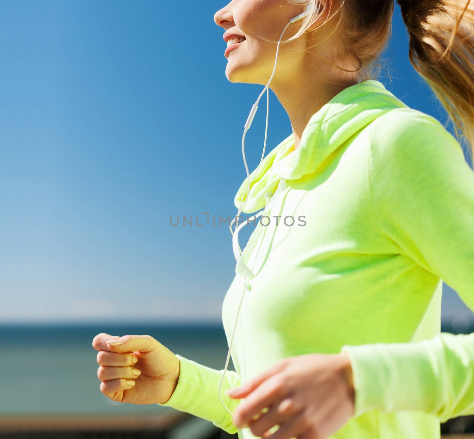 sport and healthy lifestyle concept - woman running and listening music with earphones outdoors