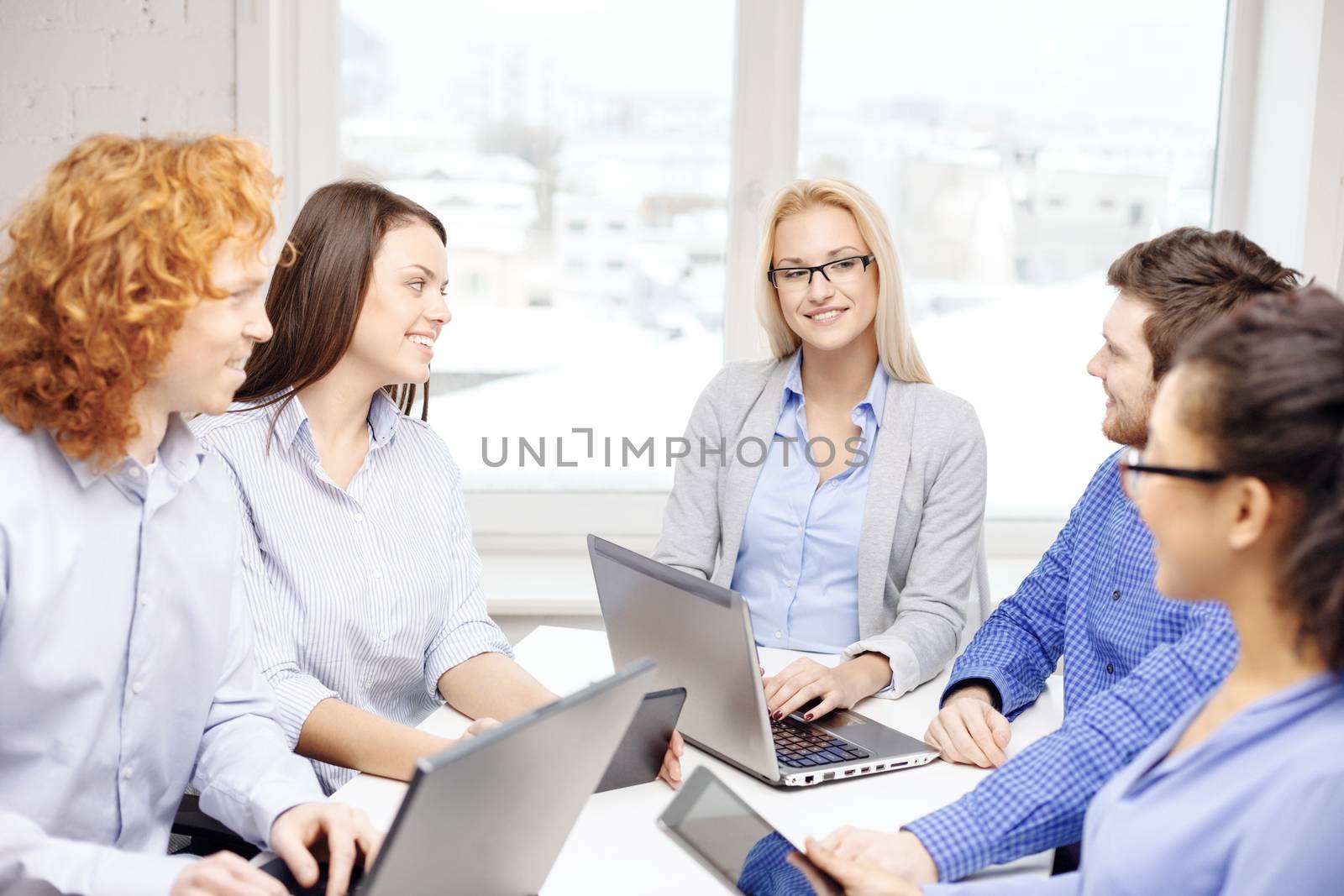 business, office and startup concept - smiling creative team with table pc and laptop computers working in office