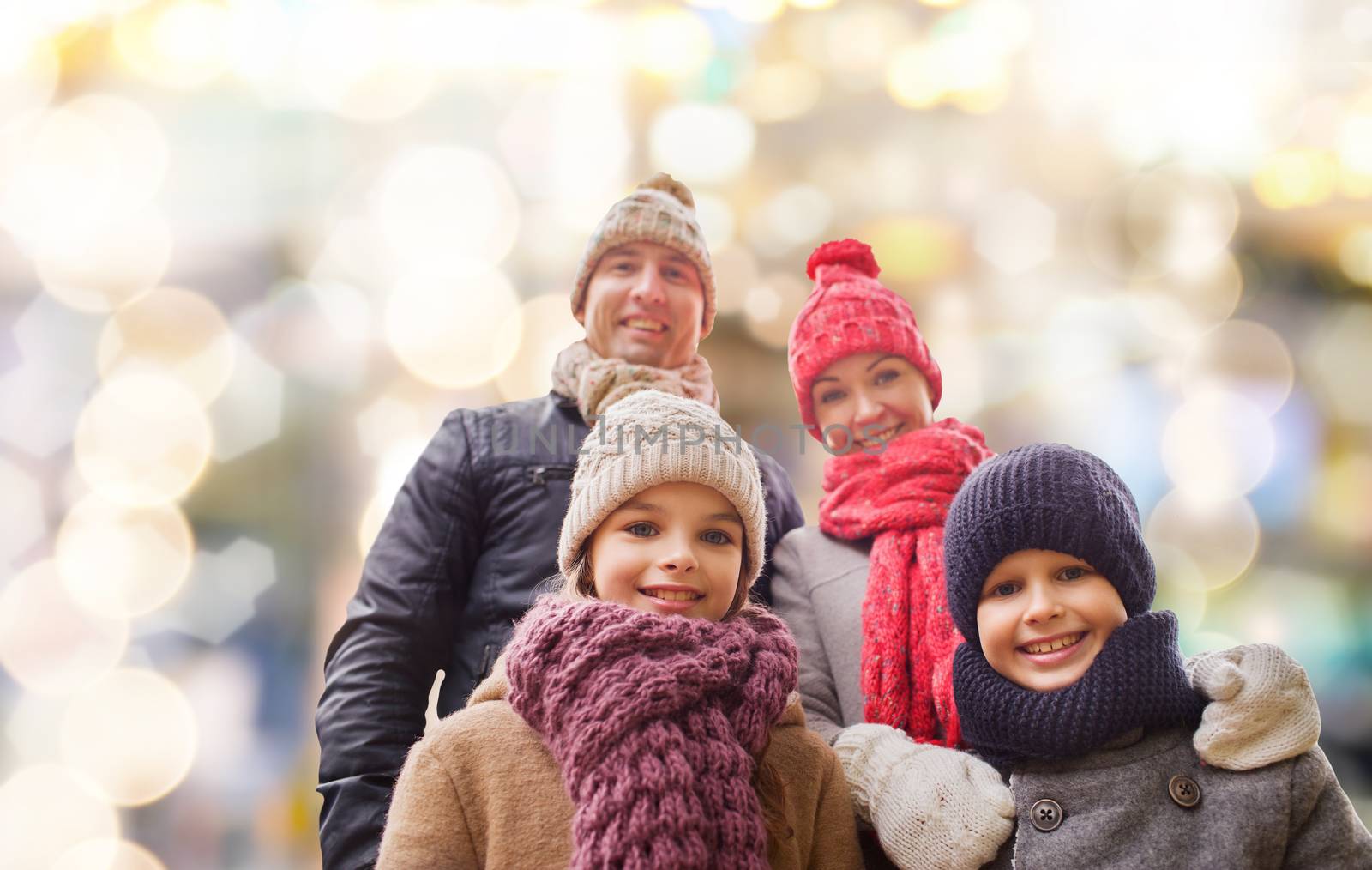 family, childhood, season, holidays and people concept - happy family in winter clothes over lights background