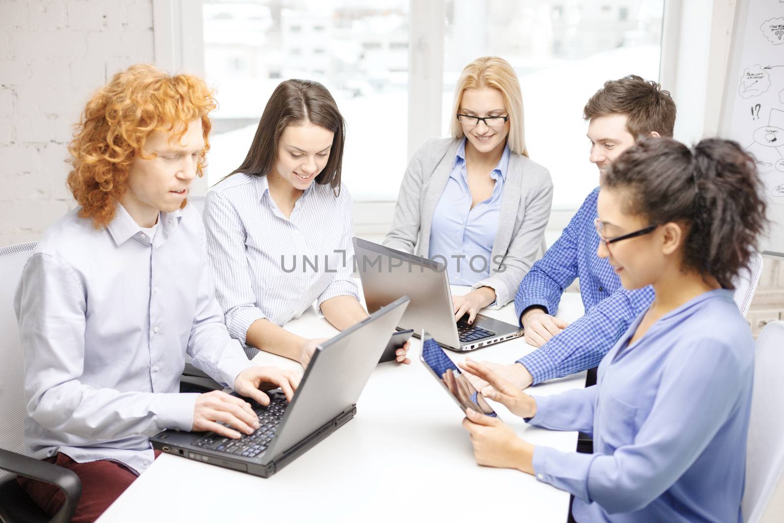 smiling team with laptop and table pc computers by dolgachov