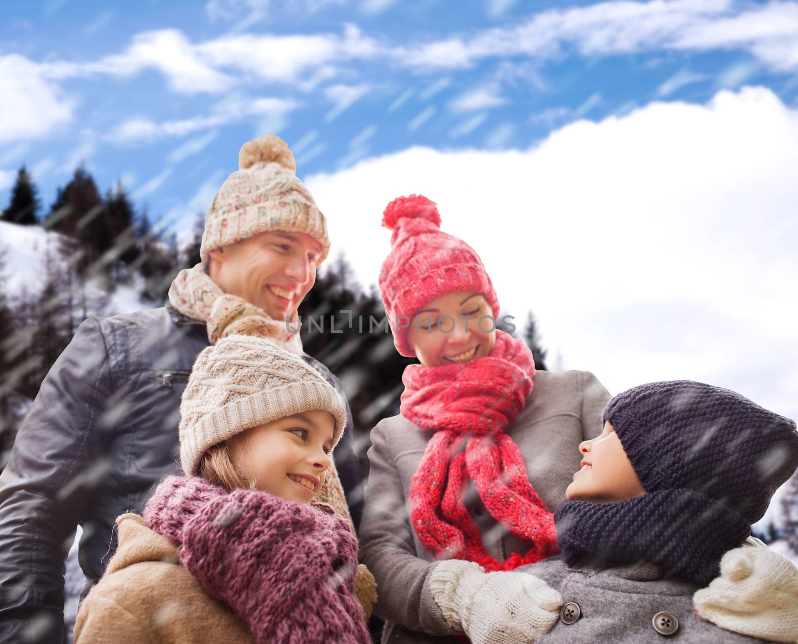 family, childhood, season and people concept - happy family in winter clothes over snowy mountains background