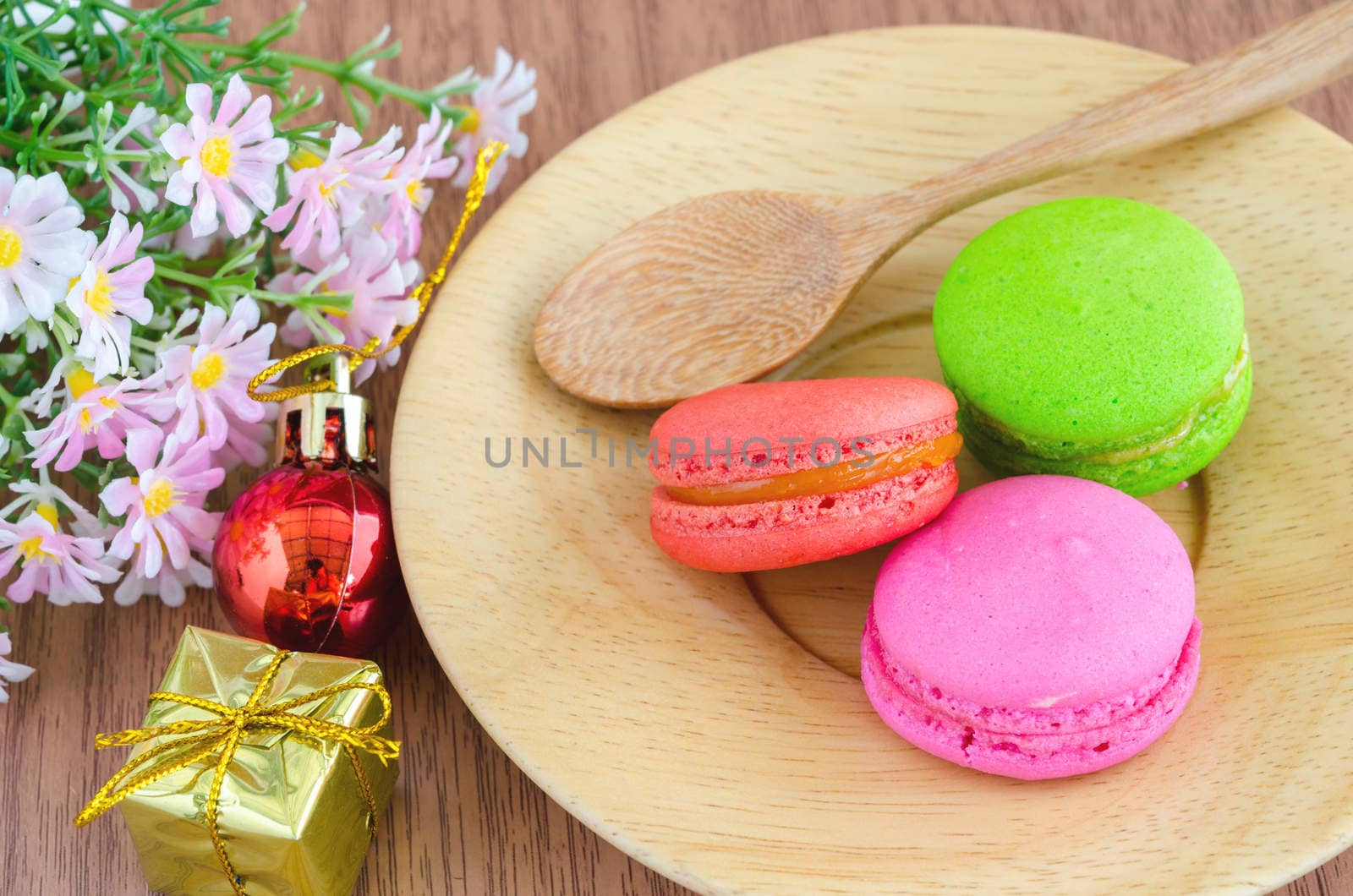 macaroons in dish wooden and christmas decoration with flower on wooden background.