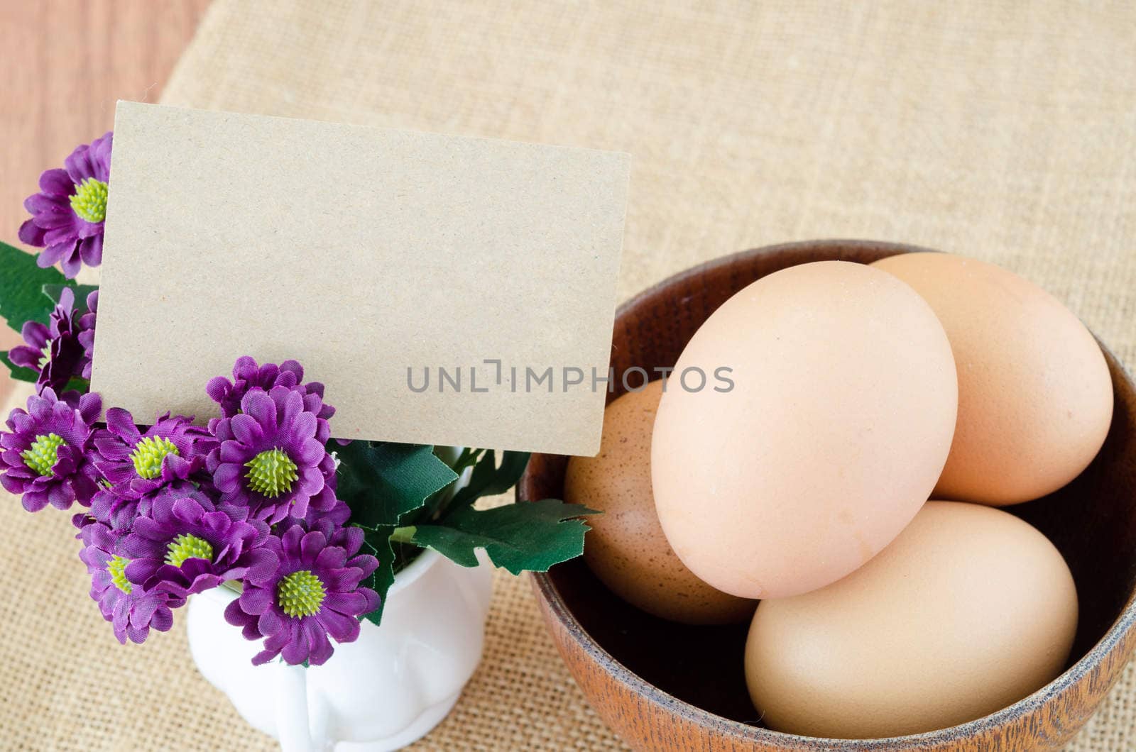 Blank card and eggs in wooden bowl on woden background.