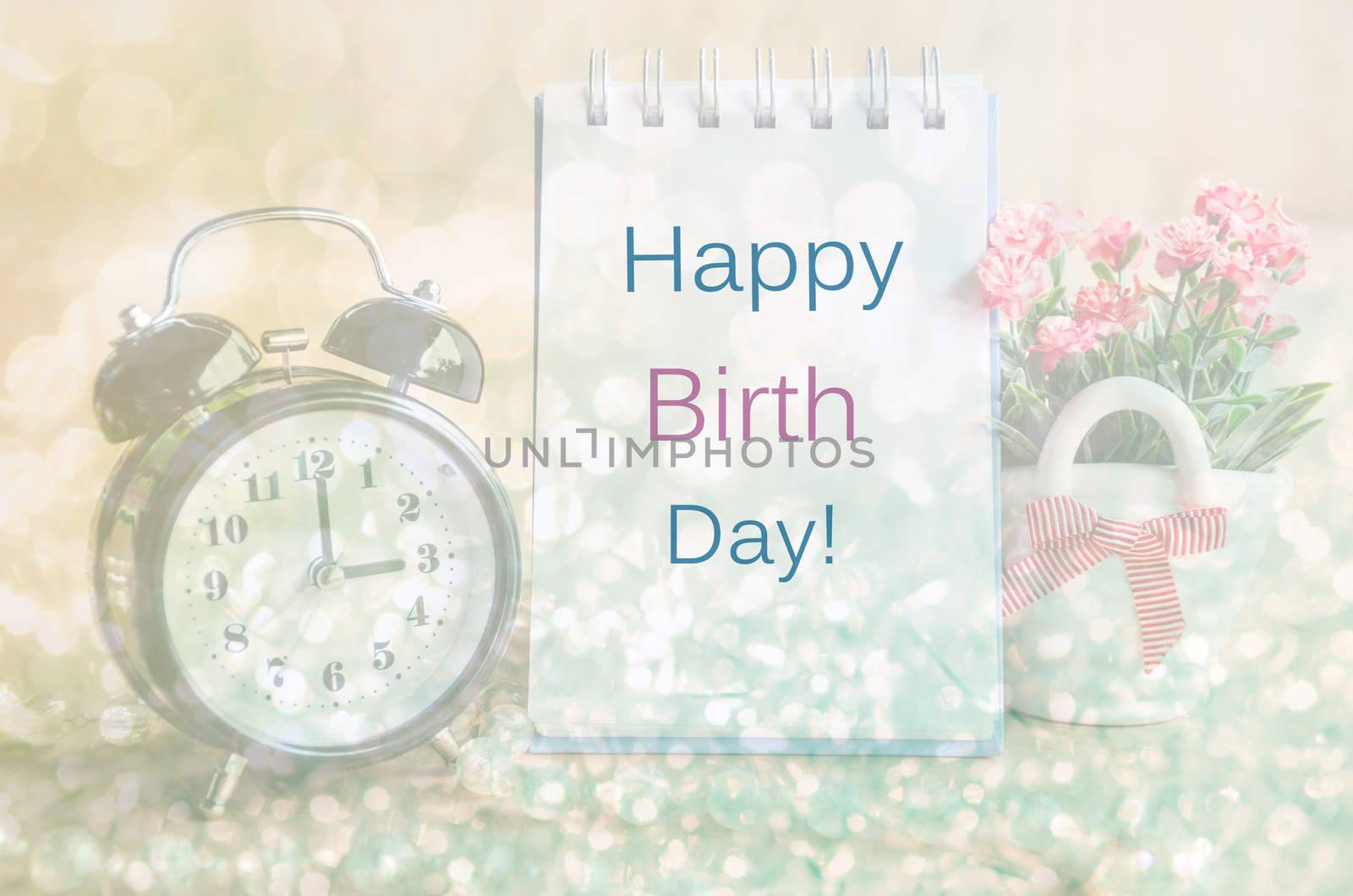Happy birth day diary and alarm clock with flowers. Soft light background.