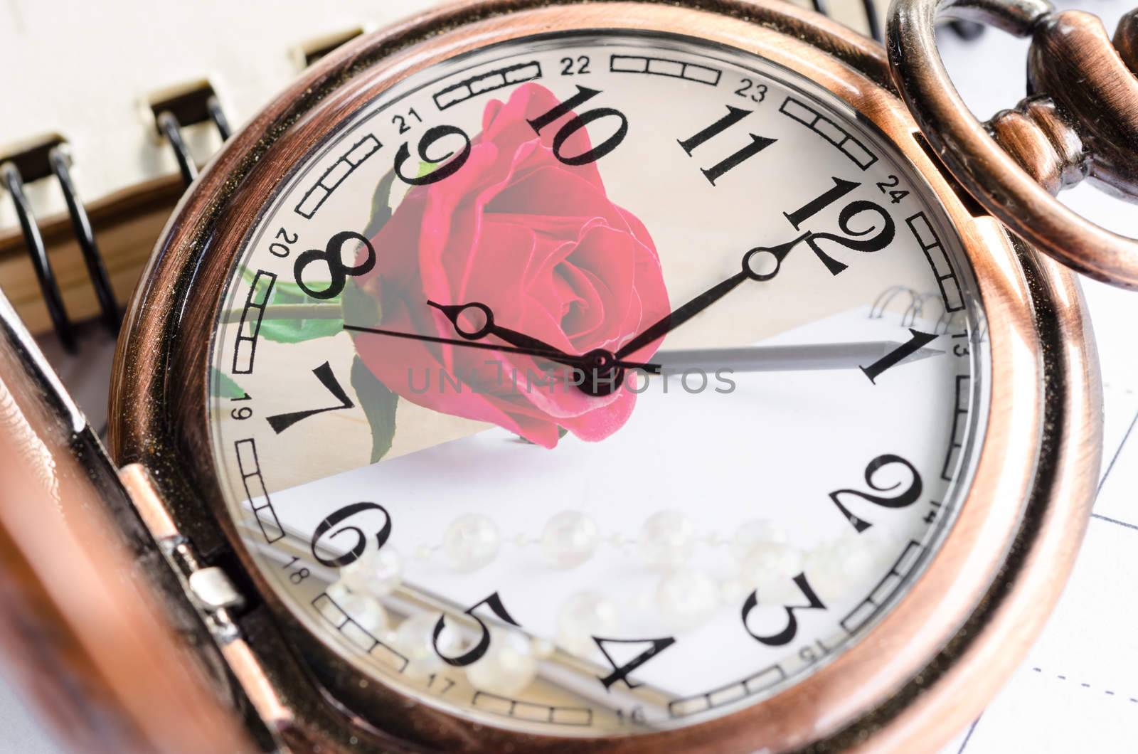 Vintage pocket watch with red rose and blank diary background. Time of love concept.