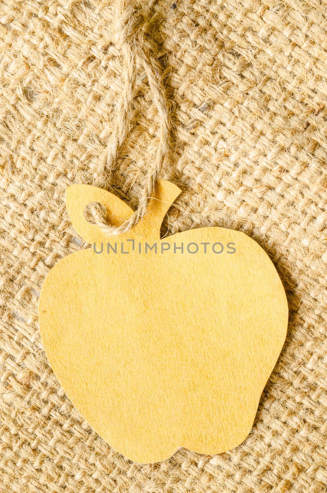 Brown blank tag apple shape on sack background. Recycle paper concept.