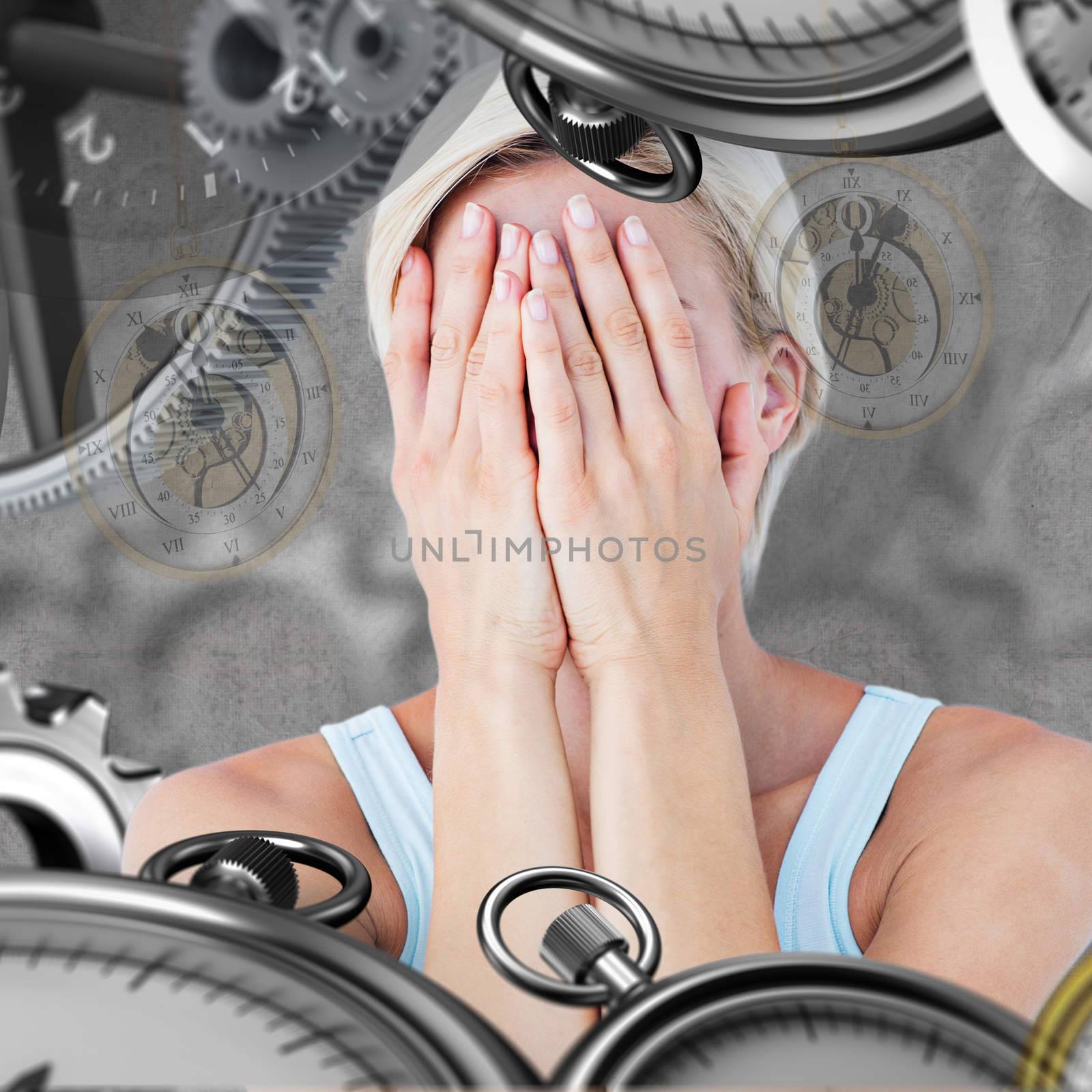 Sad blonde woman with head on hands  against grey background