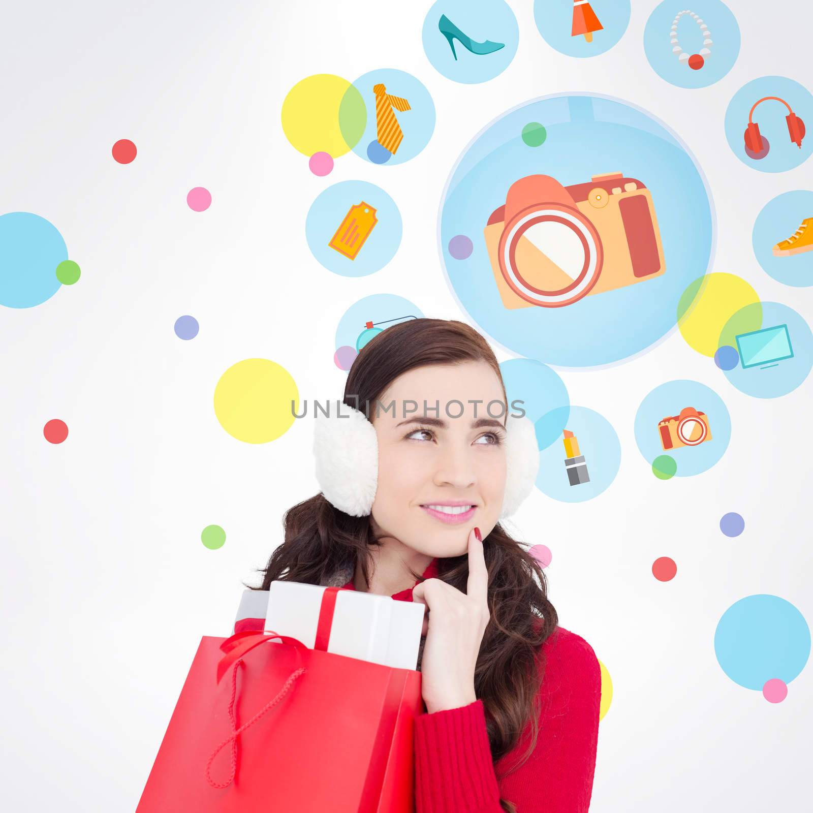 Brunette with ear muffs holding shopping bag full of gifts against dot pattern