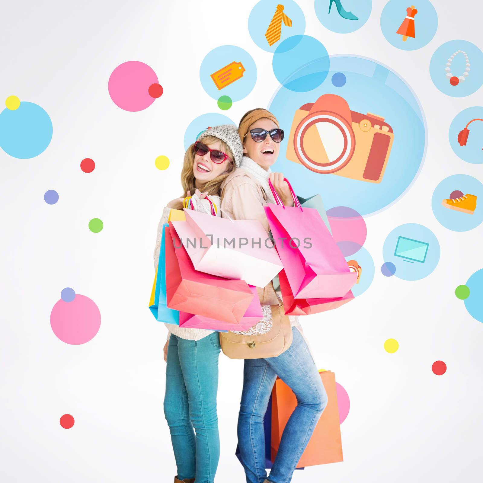 Beautiful women holding shopping bags looking at camera  against dot pattern