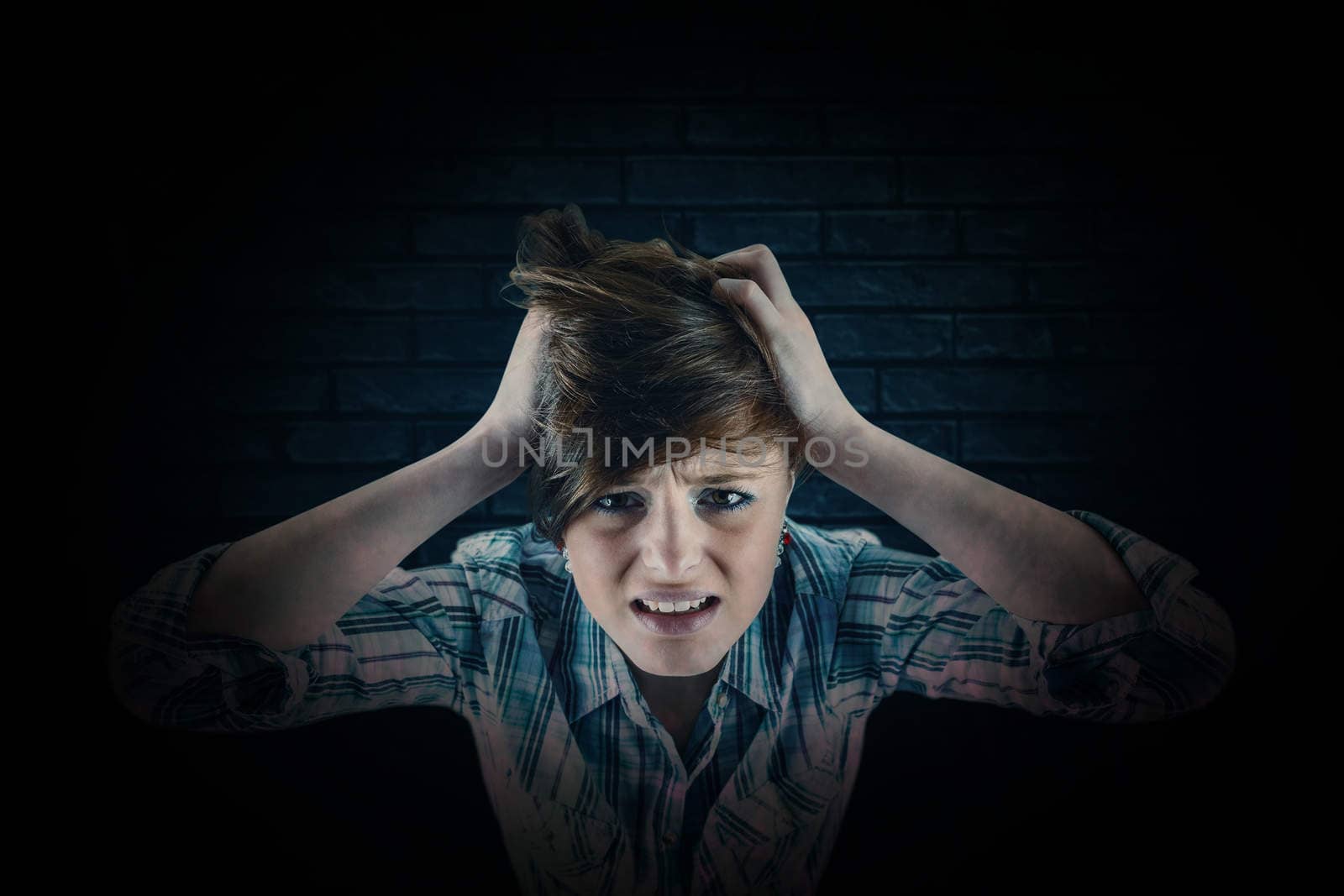 Pretty brunette getting a headache with hands on head against black background