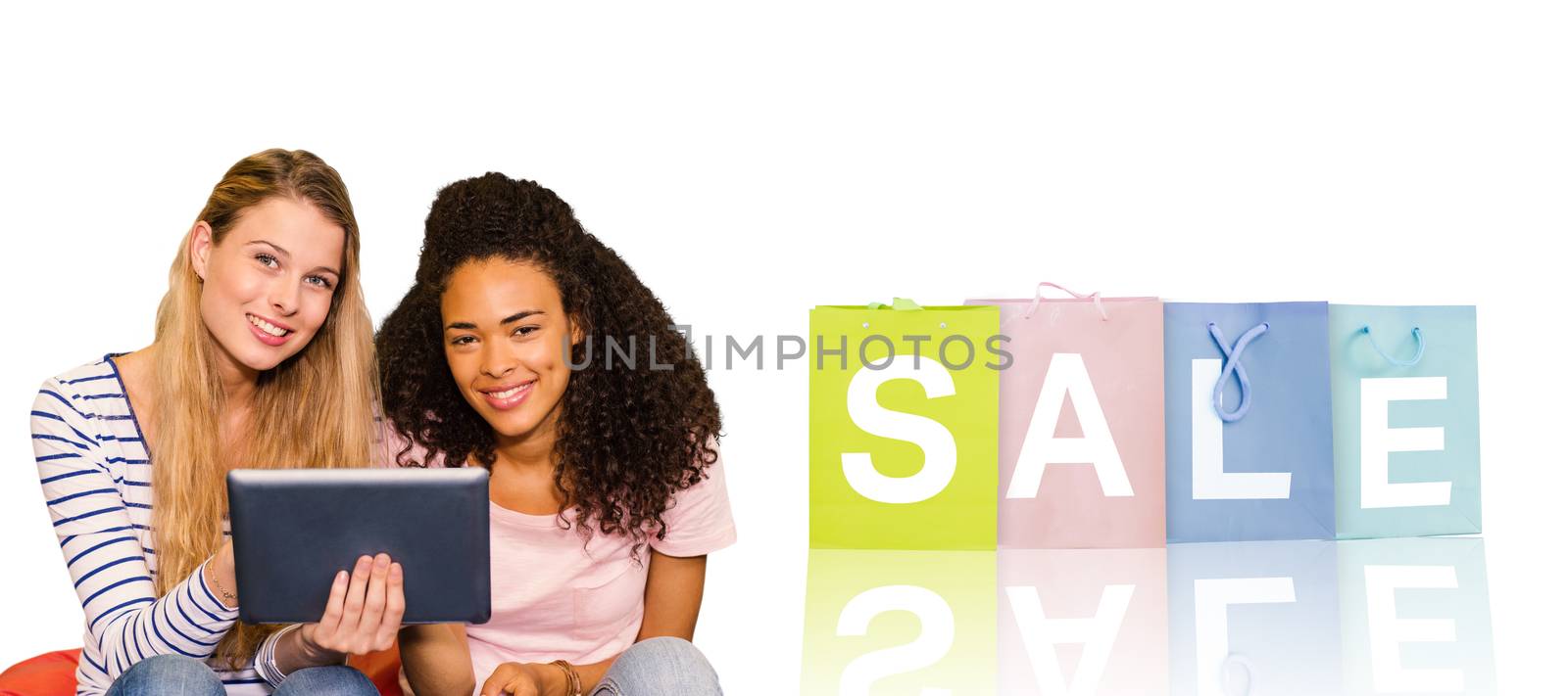 Portrait of happy female college friends using digital tablet against white background with vignette