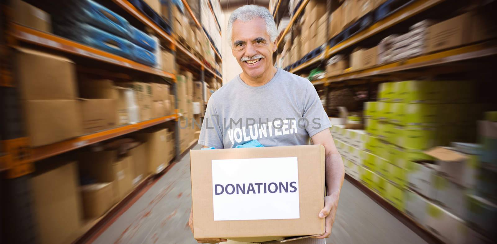 Happy volunteer senior holding donation box against worker with trolley of boxes