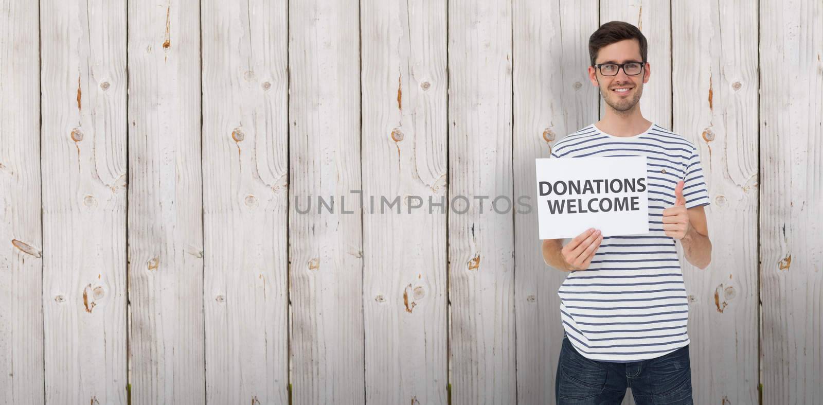 Man holding a donation welcome note while gesturing thumbs up against wooden background