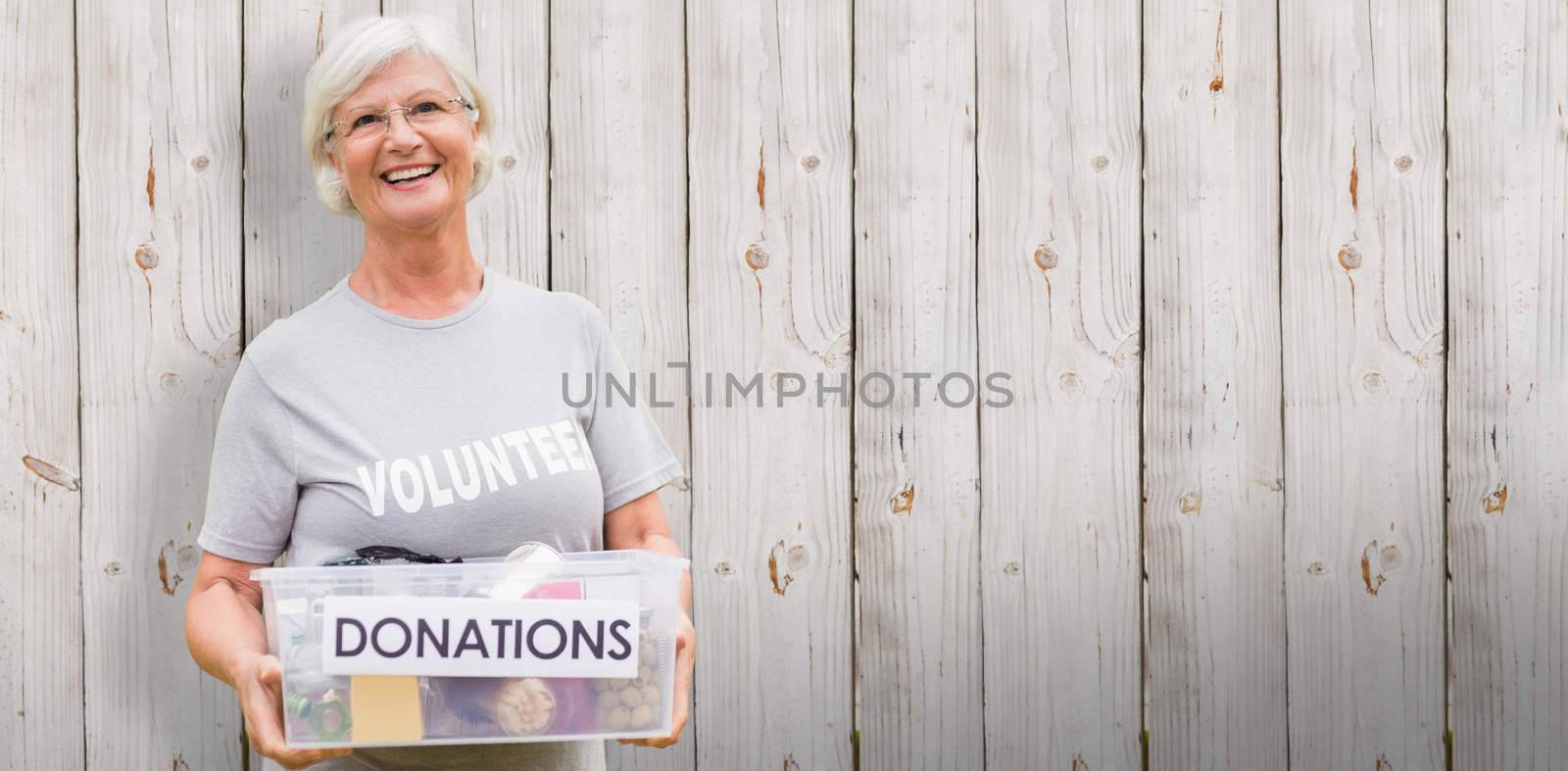 Happy grandmother holding donation box against wooden background