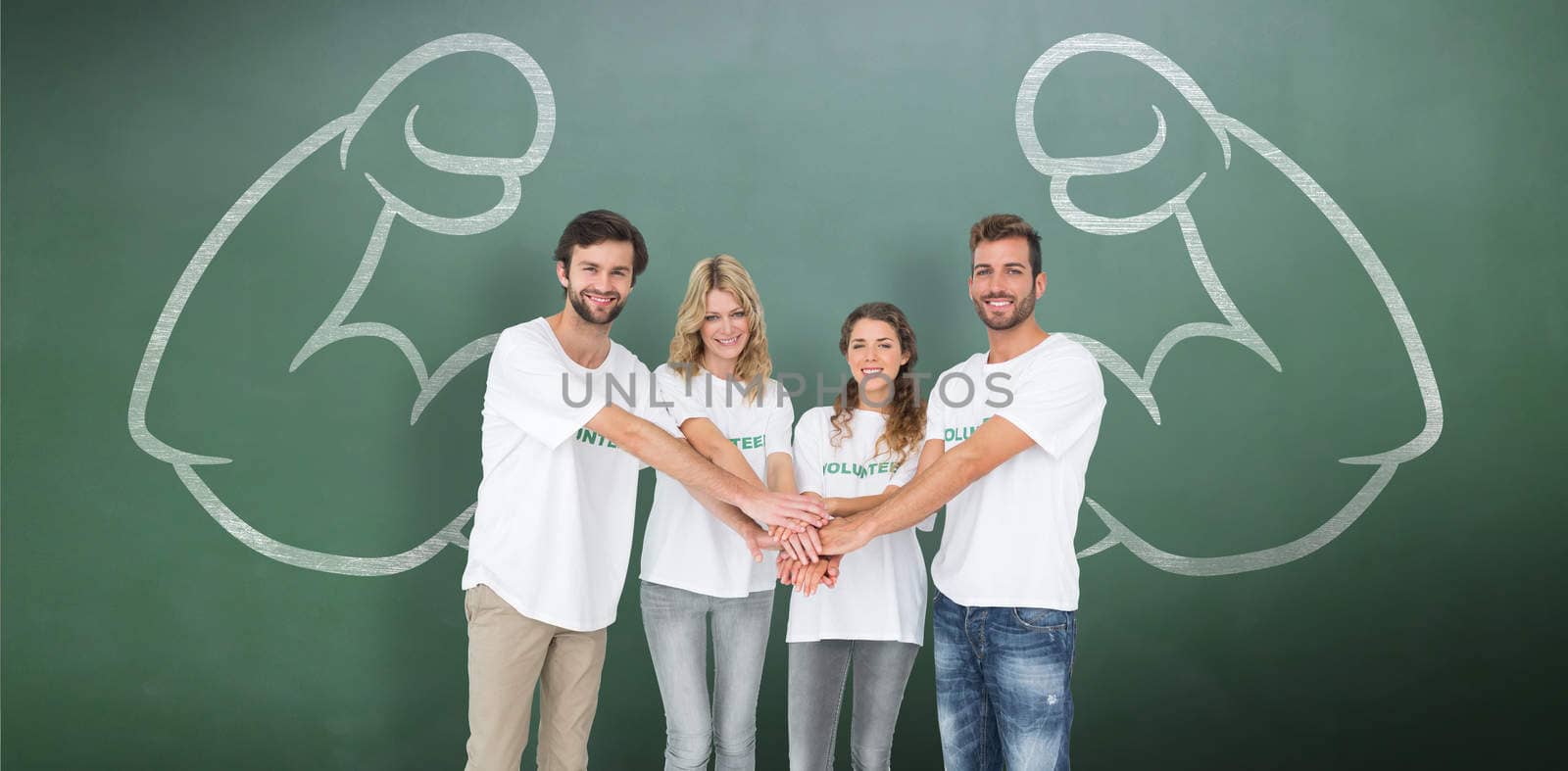 Group portrait of happy volunteers with hands together against green chalkboard