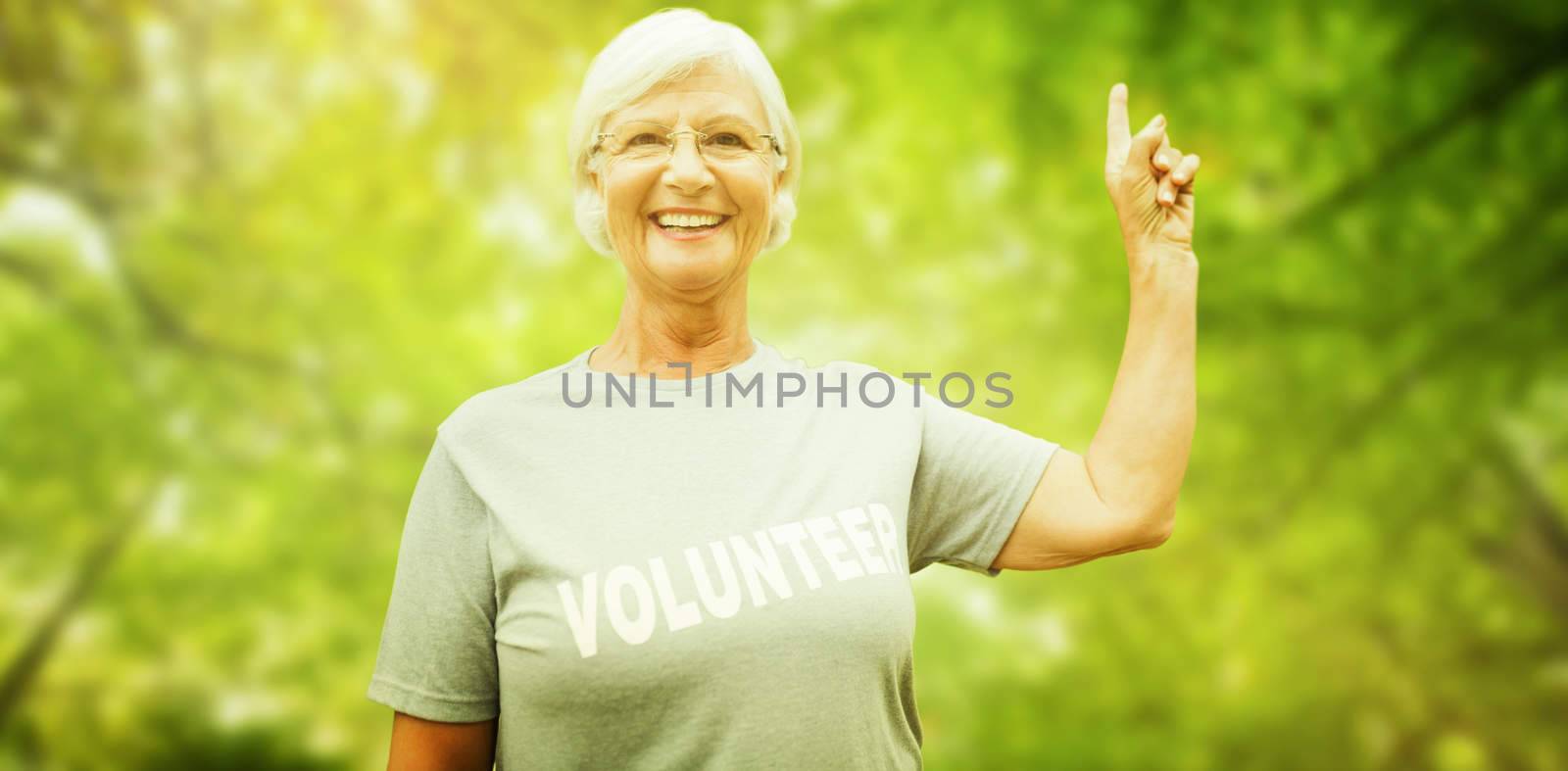Happy volunteer grandmother with thumbs up  against green leaves