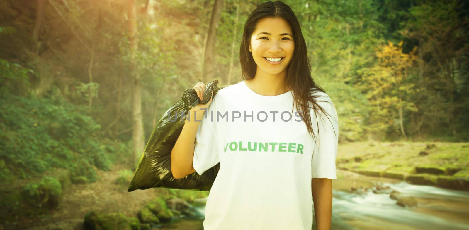 Team of volunteers picking up litter in park against rapids flowing along lush forest