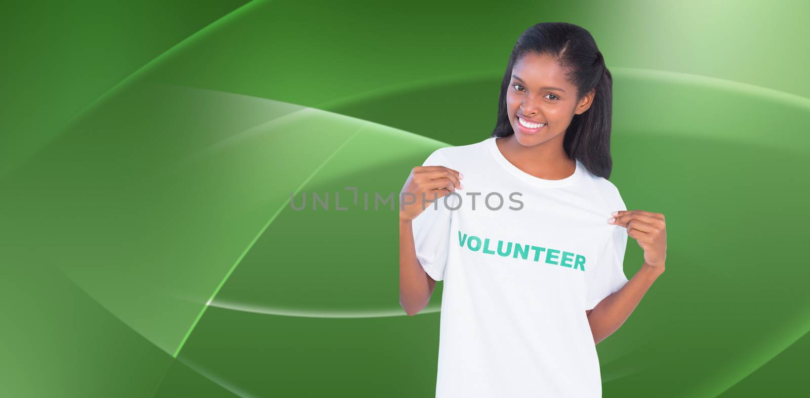 Composite image of young woman wearing volunteer tshirt and pointing to it by Wavebreakmedia