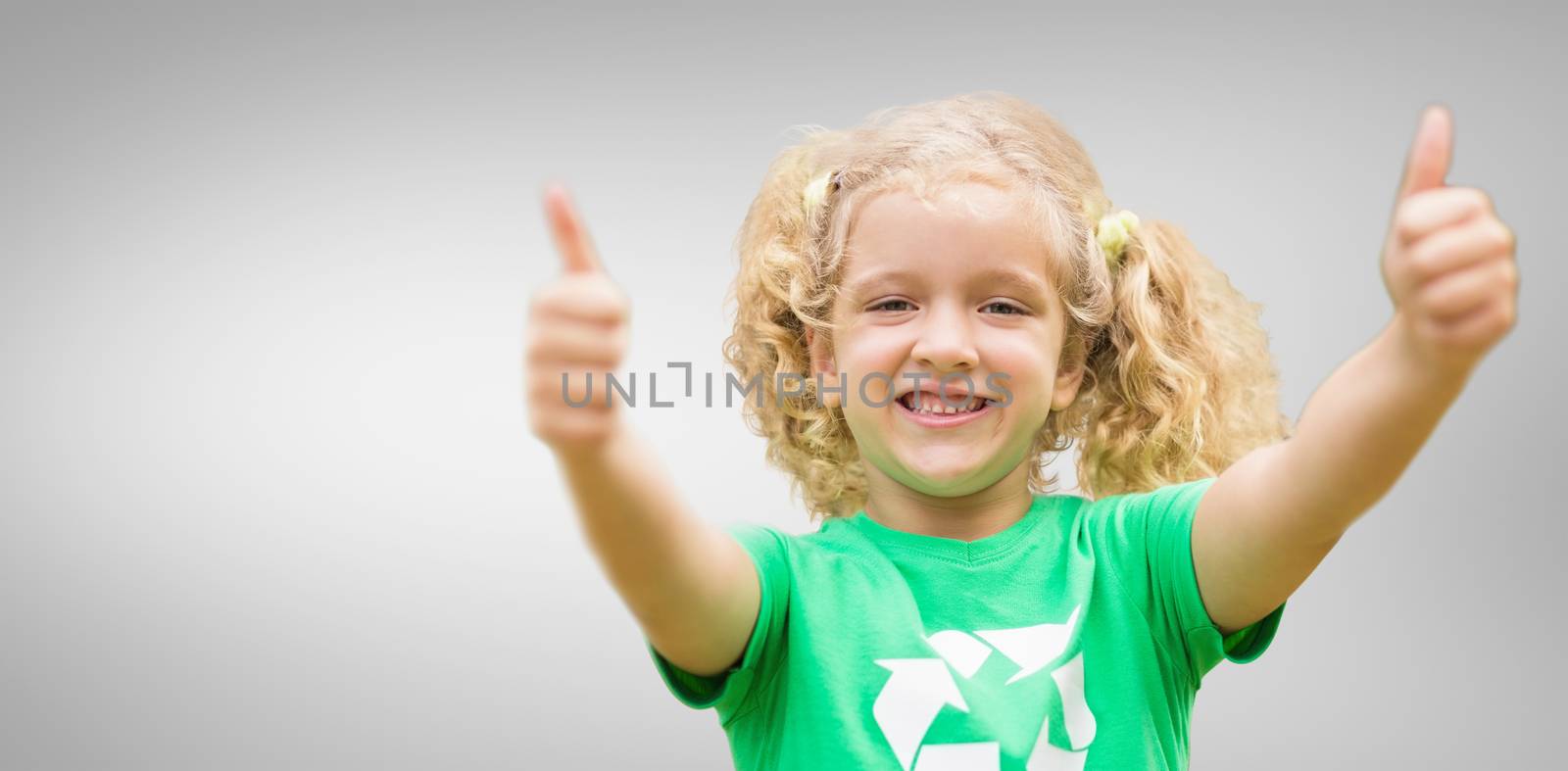 Composite image of happy little girl in green with thumbs up  by Wavebreakmedia