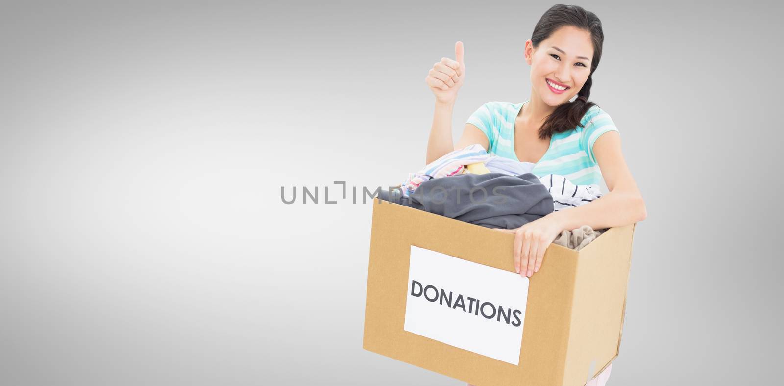 Woman with clothes donation gesturing thumbs up against grey vignette
