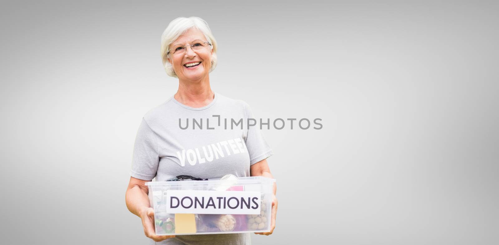 Happy grandmother holding donation box against grey vignette