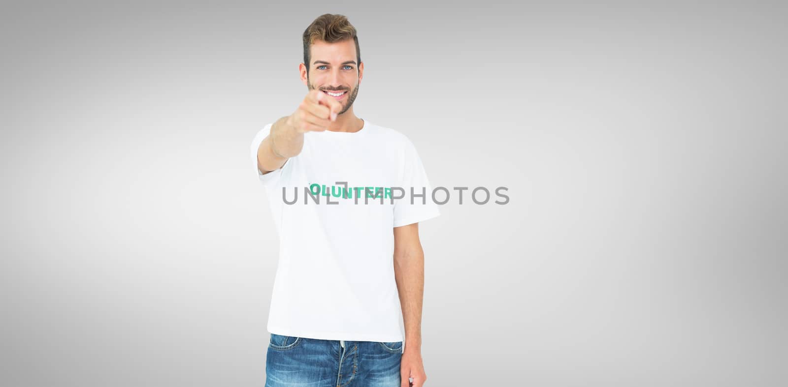 Portrait of a happy male volunteer pointing at you against grey vignette