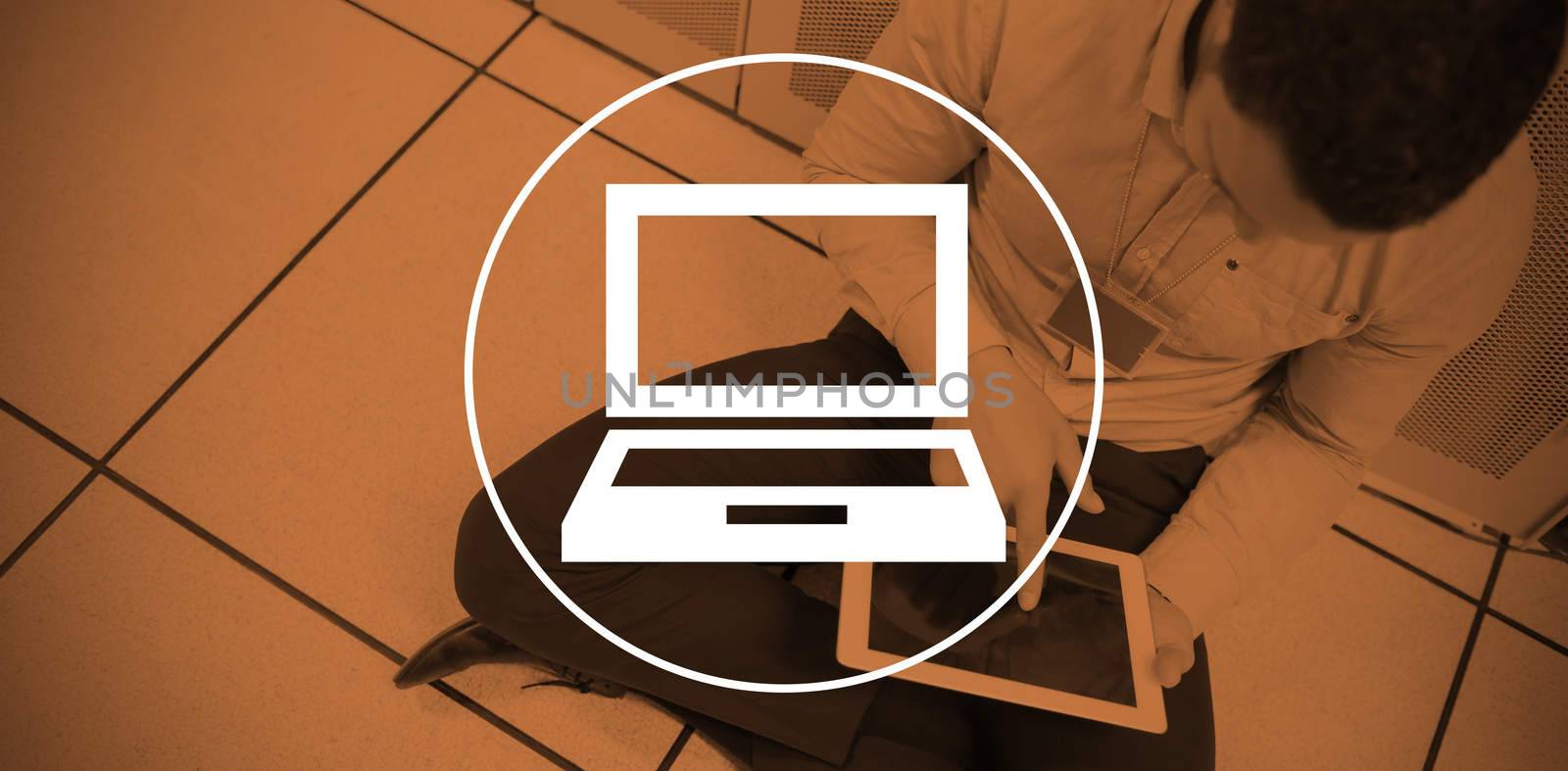 Laptop against businessman using digital tablet while sitting on office floor