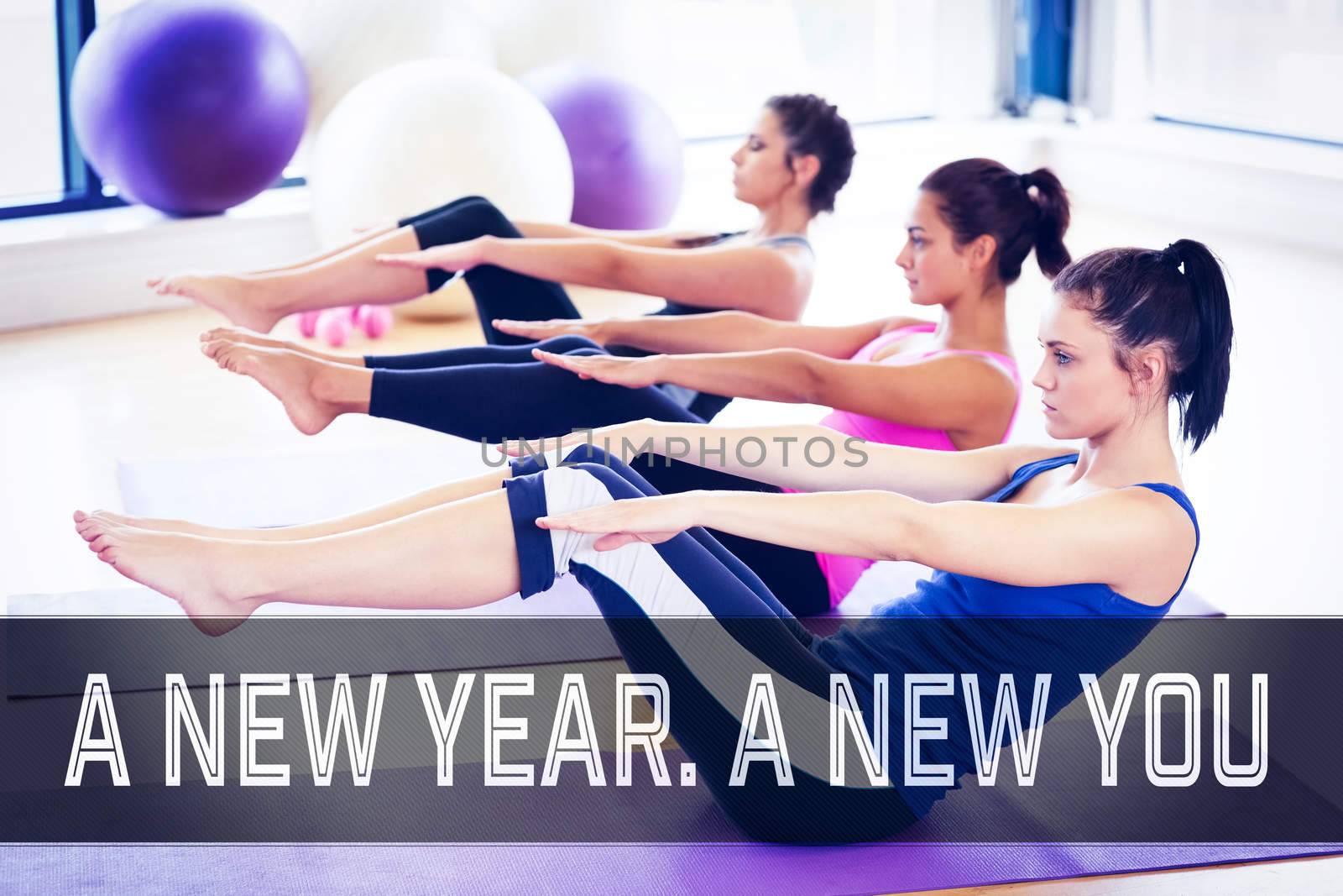 Class stretching on mats at yoga class in fitness studio against motivational new years message