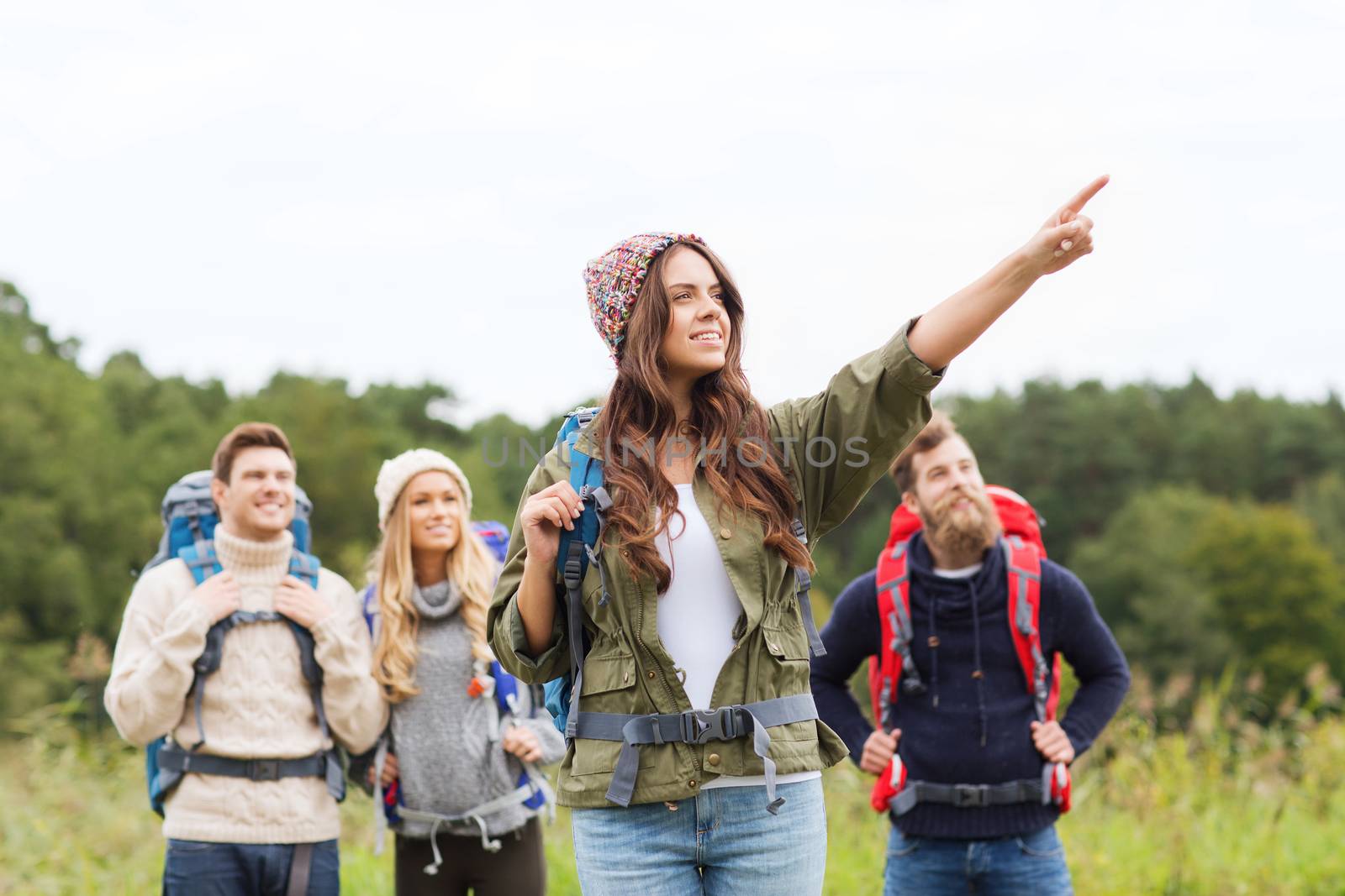 smiling hikers with backpacks pointing finger by dolgachov