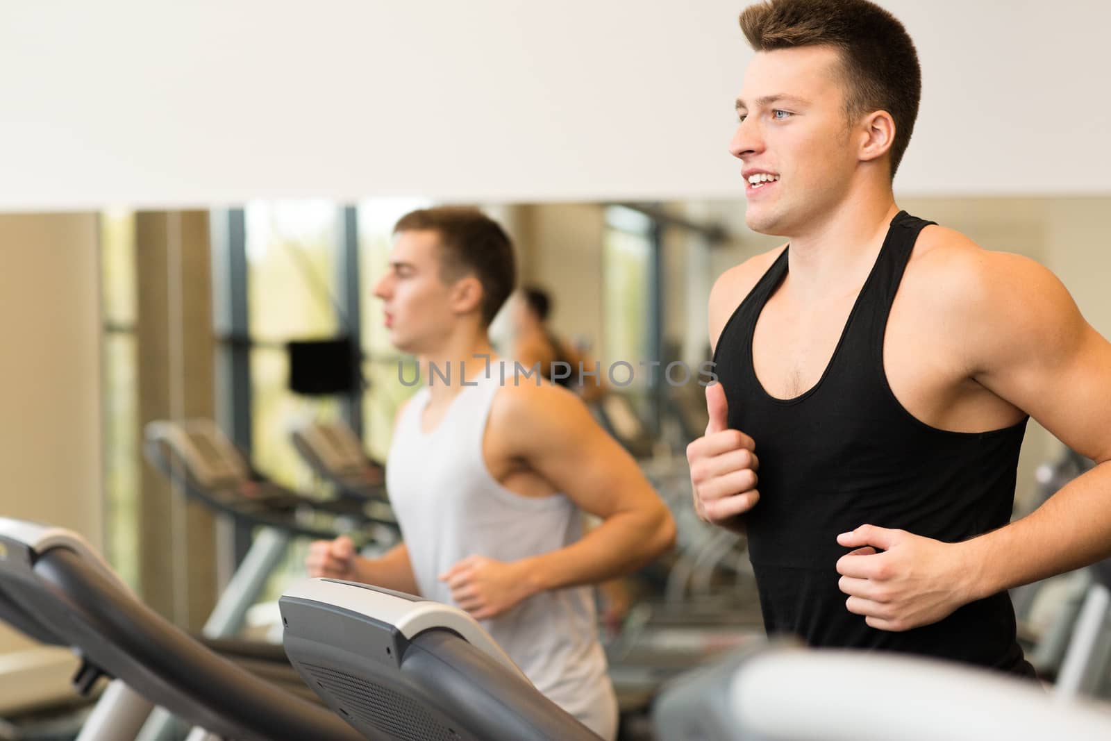 smiling men exercising on treadmill in gym by dolgachov