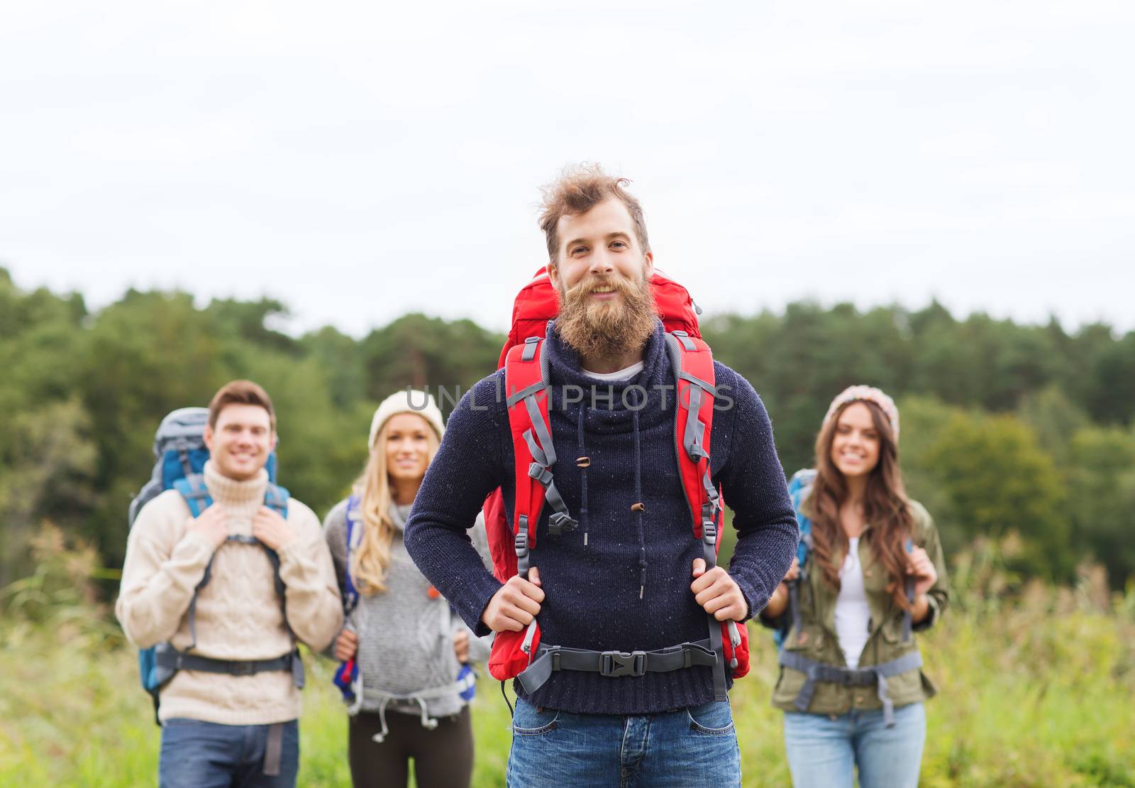 group of smiling friends with backpacks hiking by dolgachov