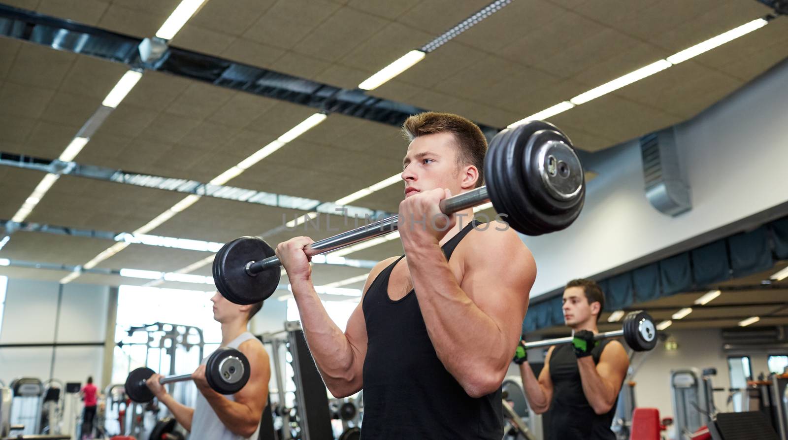 sport, bodybuilding, lifestyle and people concept - group of men with barbell flexing muscles in gym