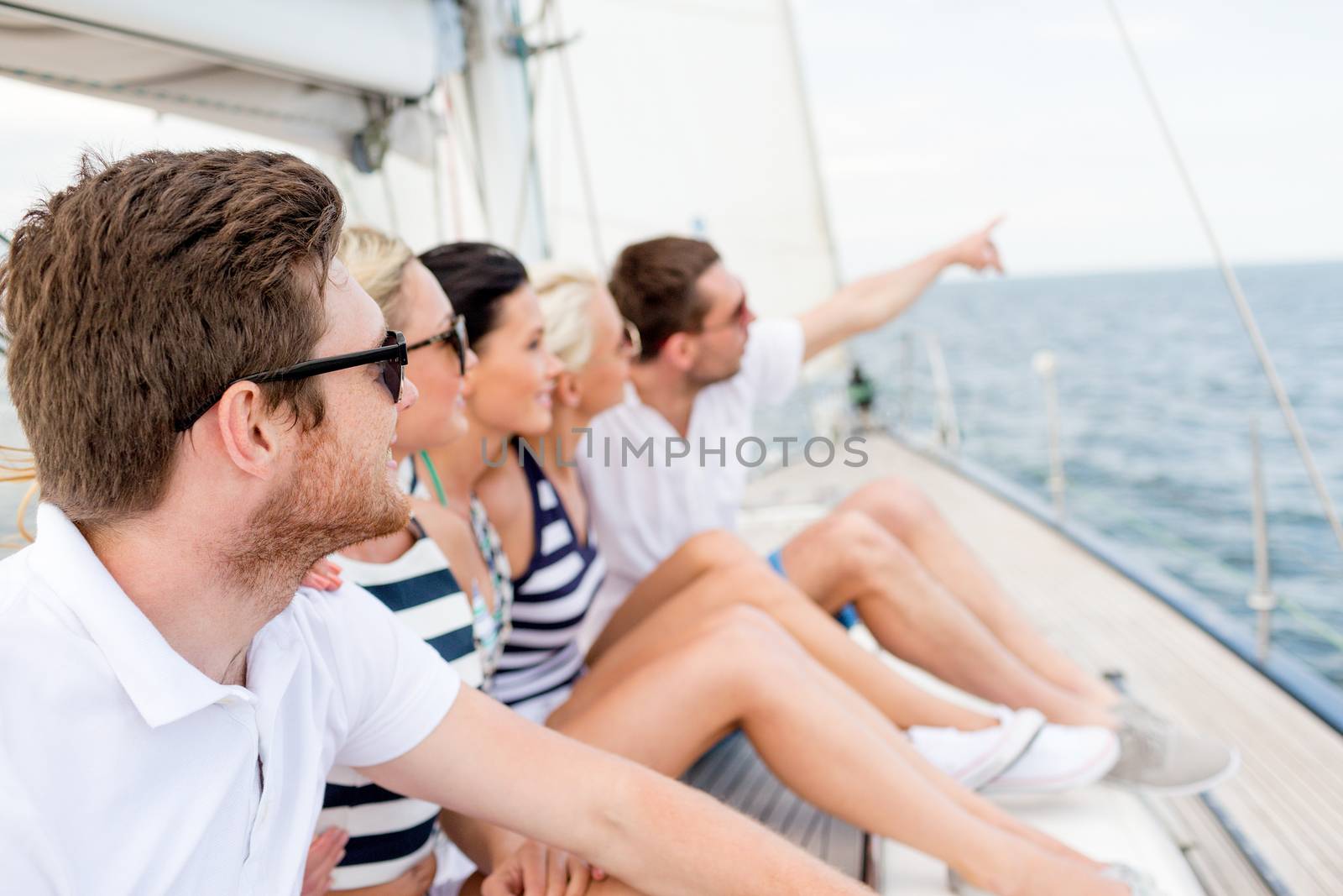 smiling friends sitting on yacht deck by dolgachov