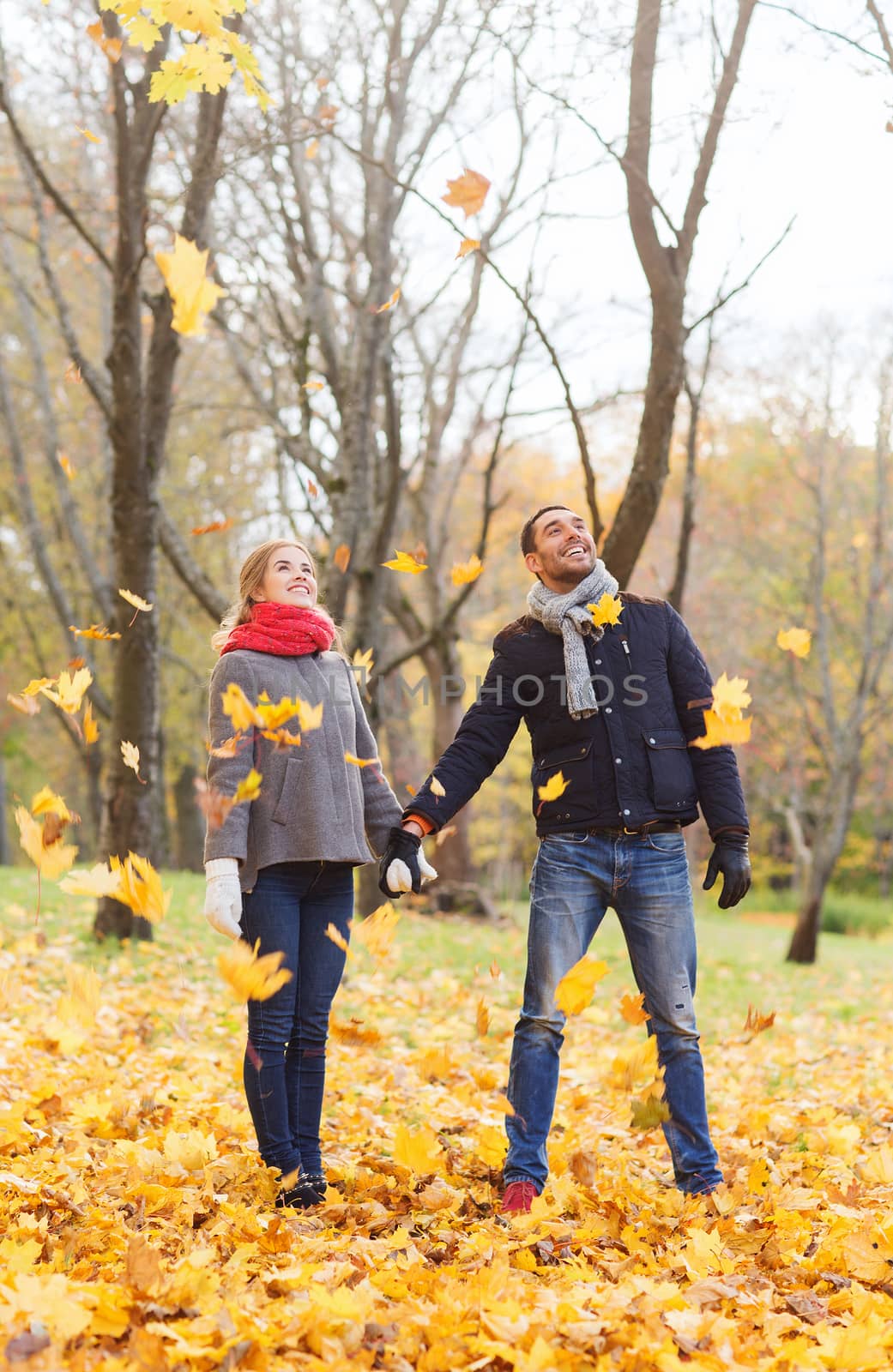 love, relationship, family, season and people concept - smiling couple throwing leaves and having fun in autumn park