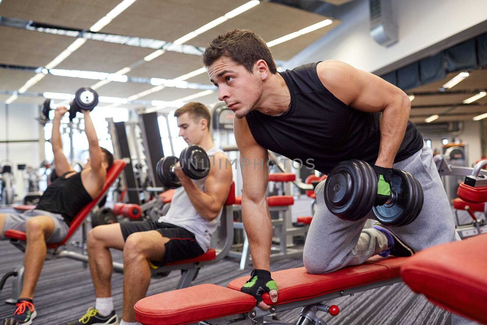 group of men with dumbbells in gym by dolgachov