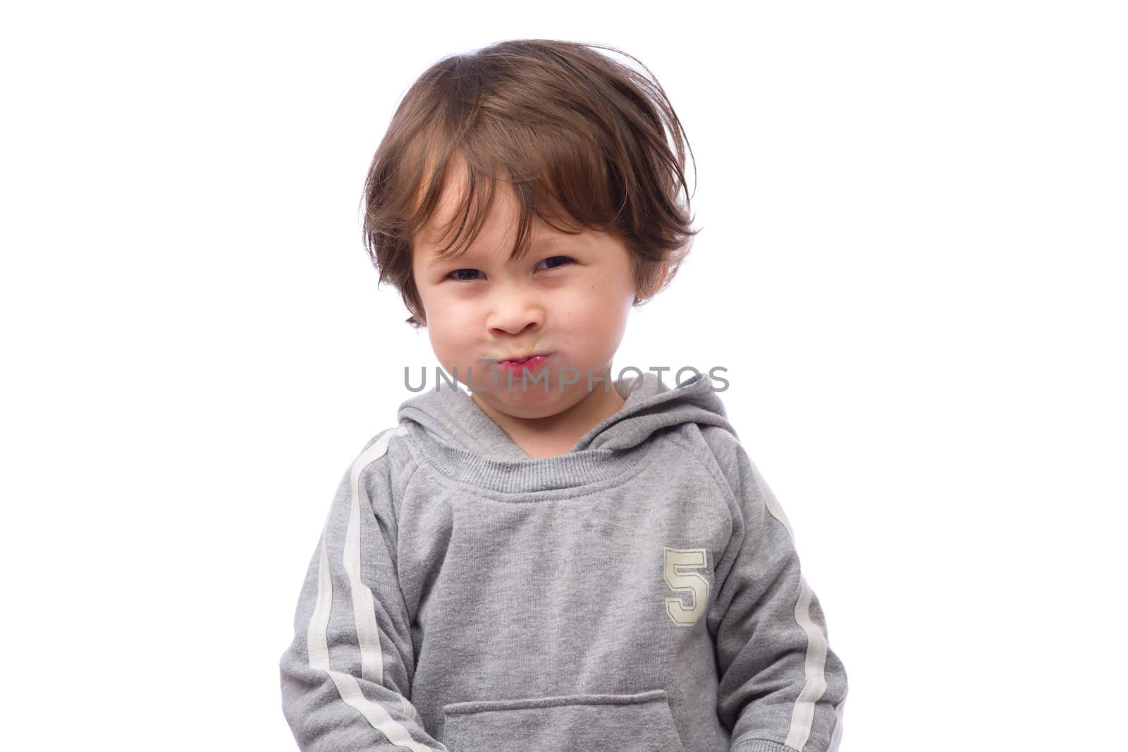 A cute 3 year old boy with an angry expression on a white background.