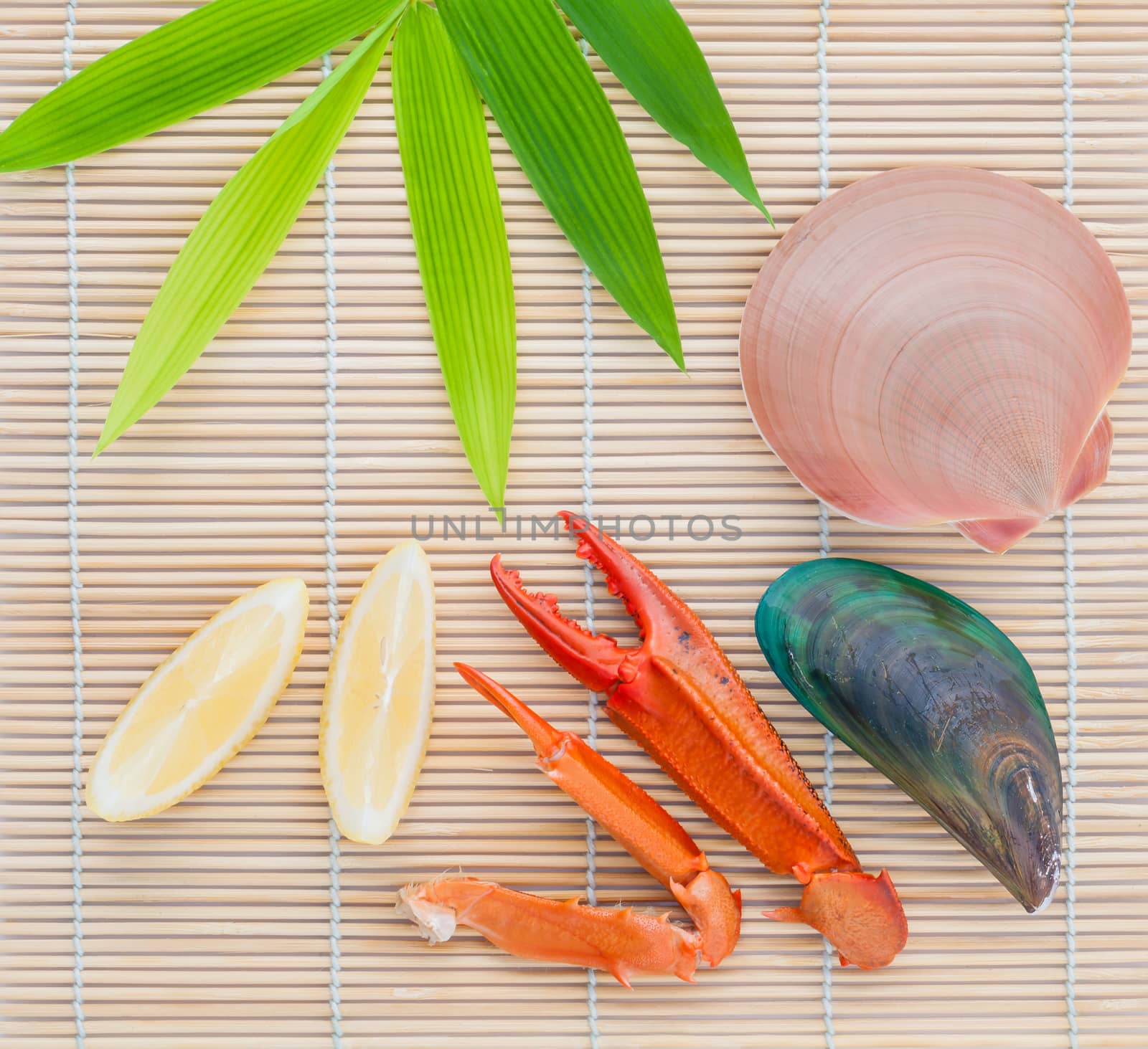 Raw queen scallops ,mussel and crab claws with lemon slice  on bamboo background and  bamboo leaves .