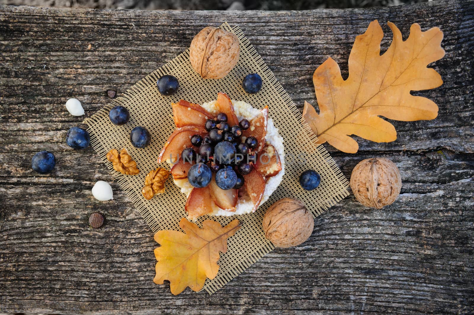 Romantic autumn still life with basket cake, walnuts, blackthorn berries and leaves, top view