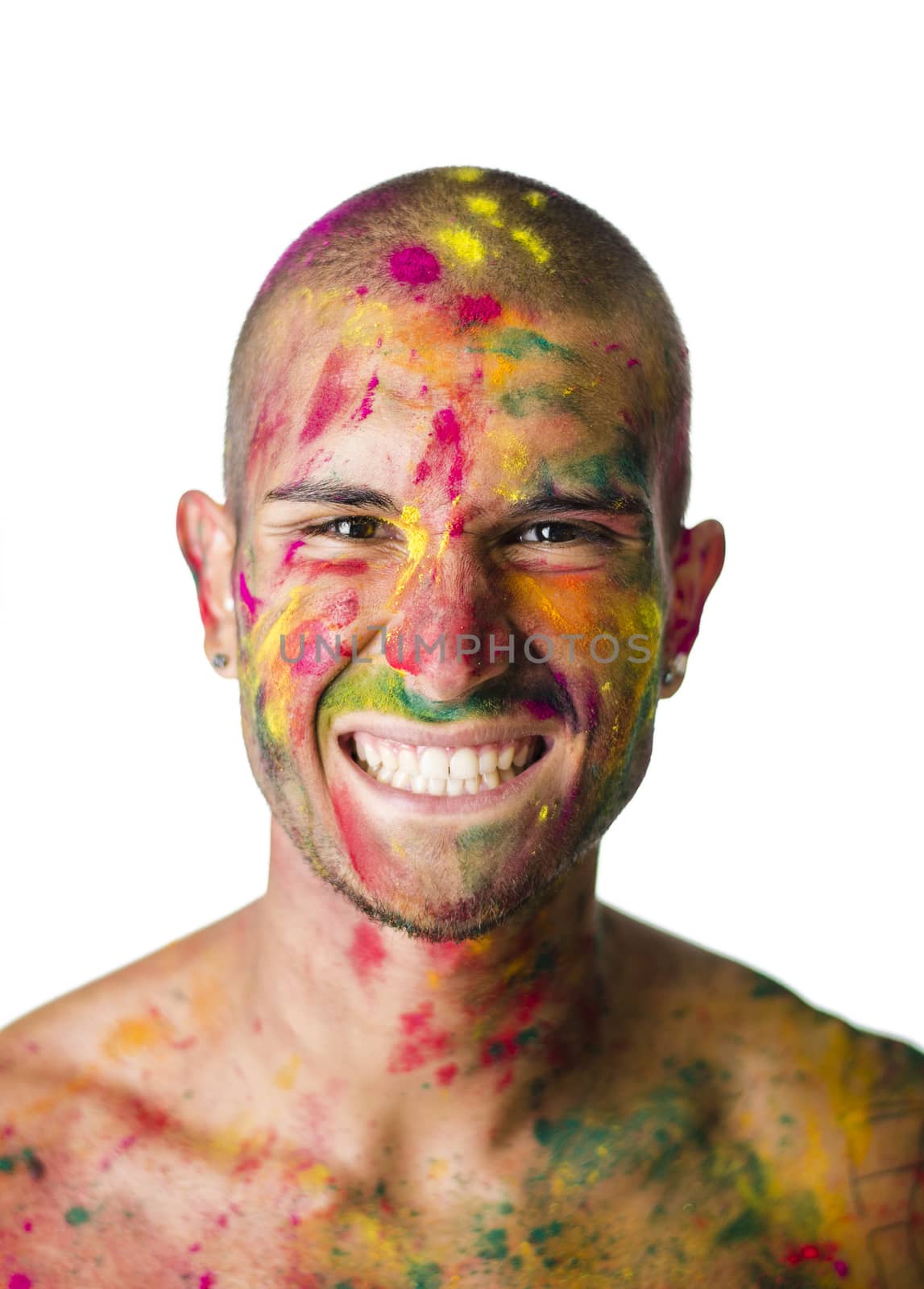 Head and shoulders shot of attractive smiling young man shirtless, skin painted all over with bright Holi colors, looking at camera, isolated on black background