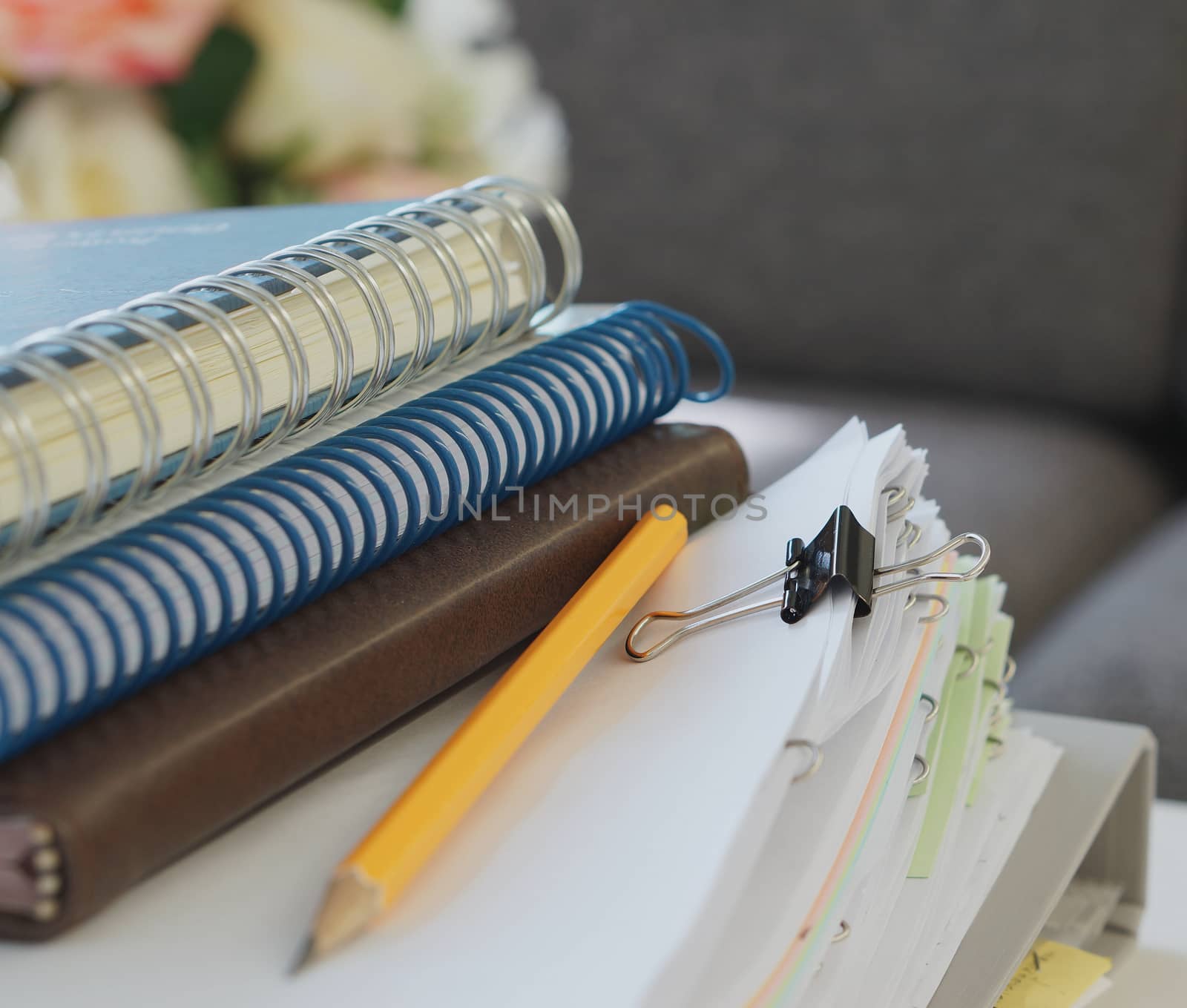 Notebooks, yellow pencil, stack of document and file placed on desk at office.