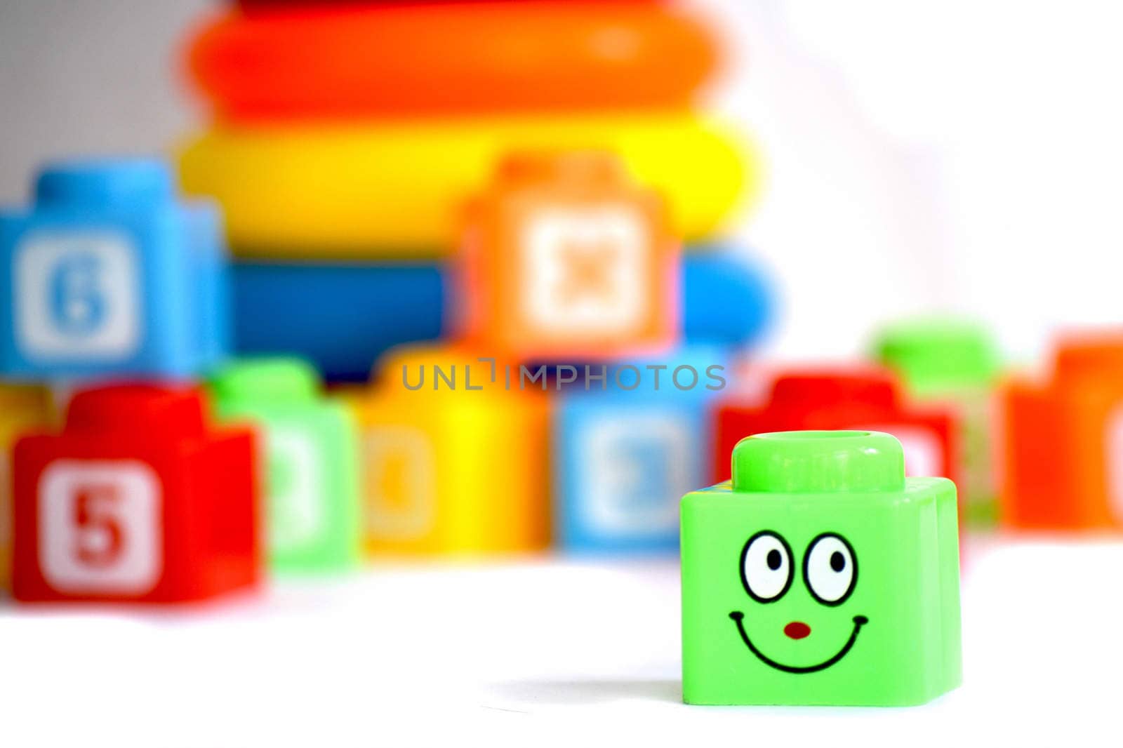 Smiling toy cube with shapes and pyramid in the background.