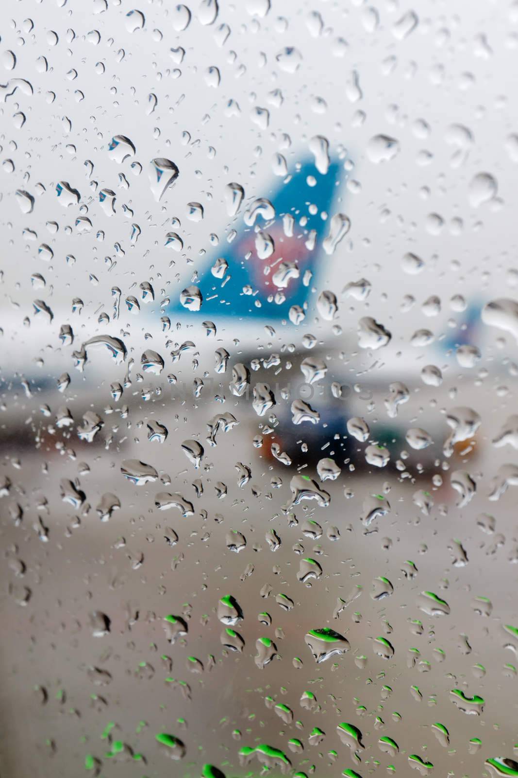 Water drops on an aircraft window with airplanes on a background