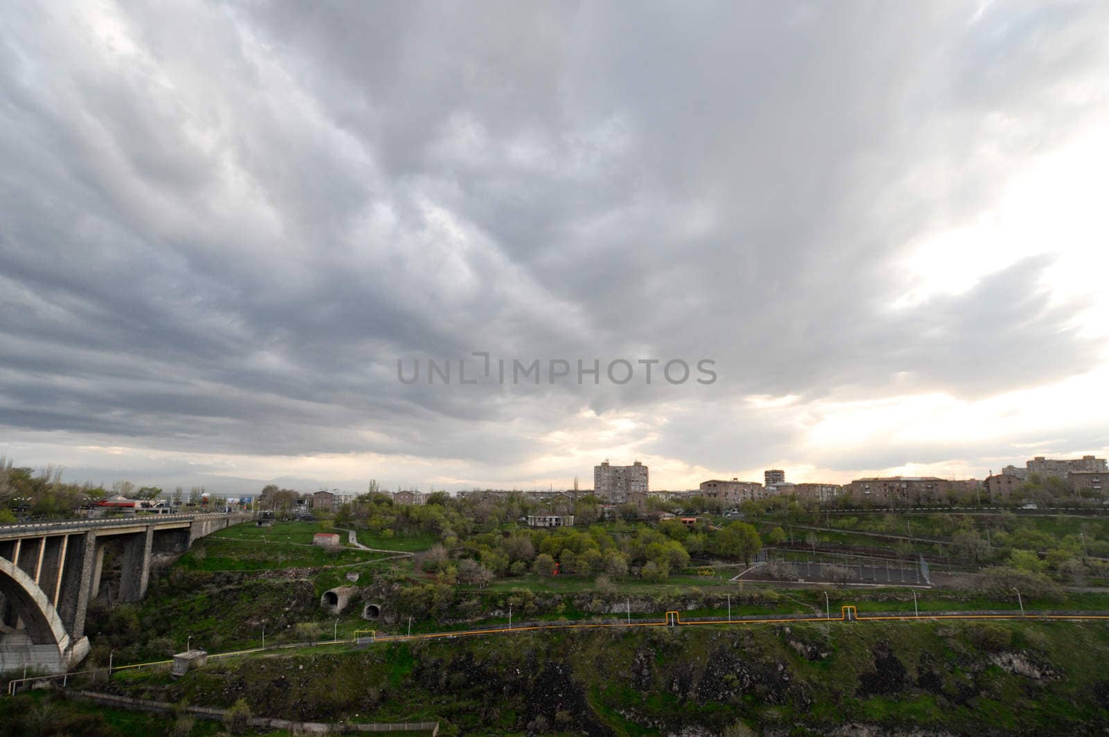 landscape with a cloudy sky, green grass and the bridge