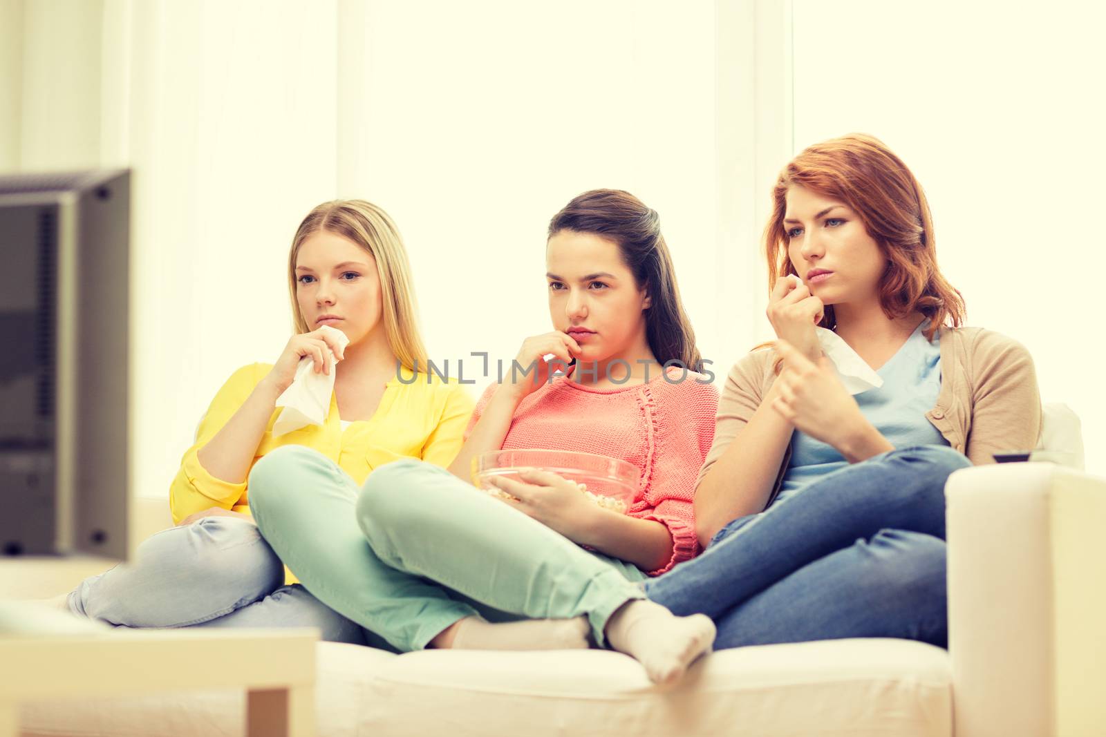 home, technology and friendship concept - three sad teenage girl watching tv at home and eating popcorn