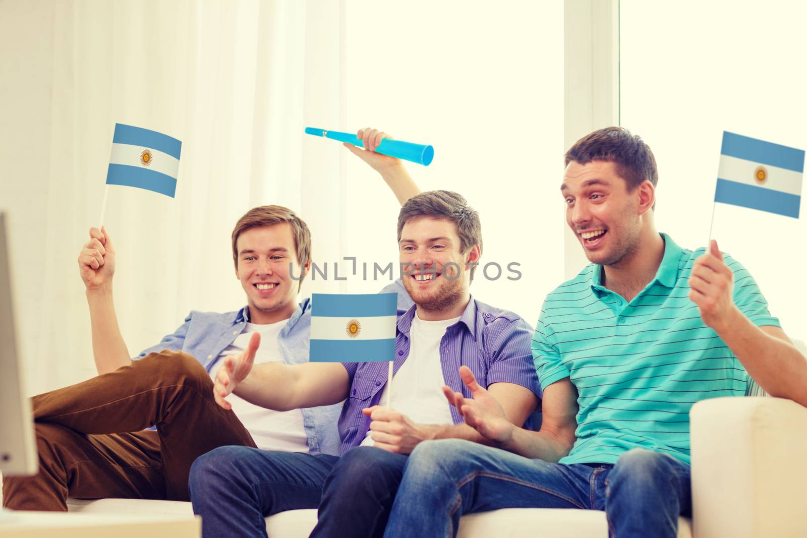 friendship, sports and entertainment concept - happy male friends with flags and vuvuzela supporting football team at home